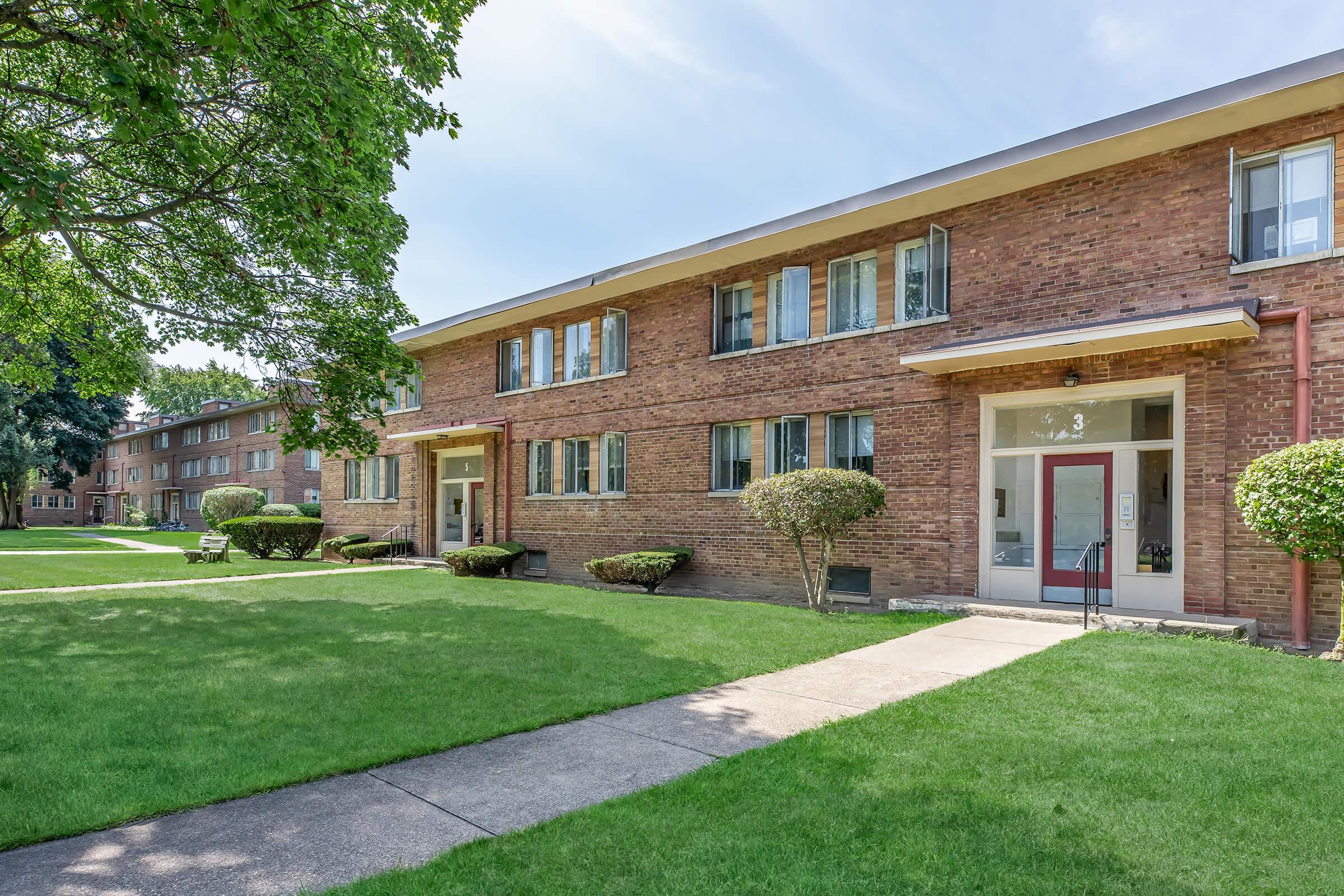 a large brick building with grass in front of a house