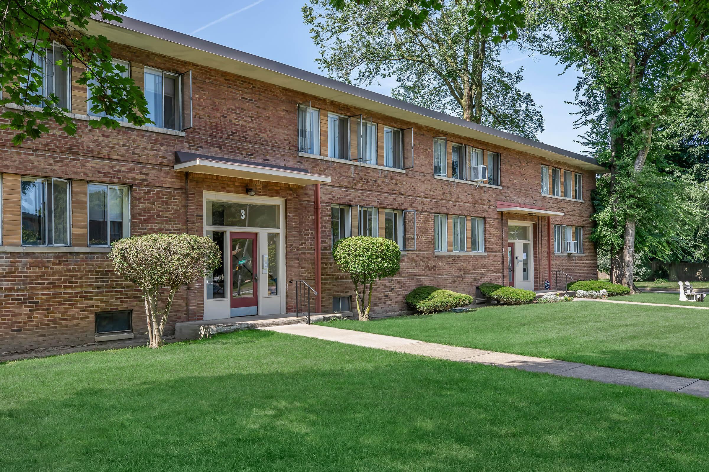 a house with a lawn in front of a brick building