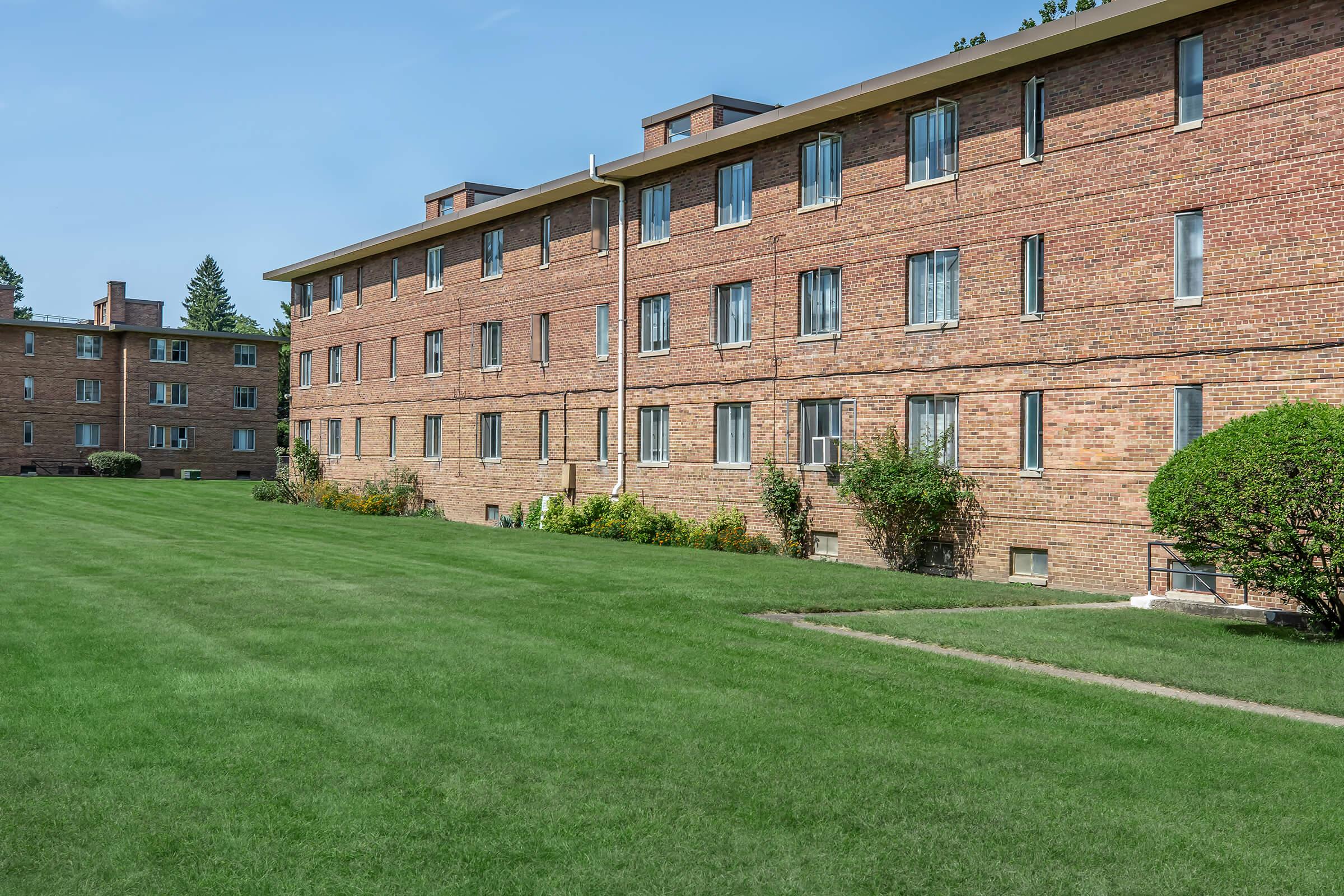 a large brick building with green grass