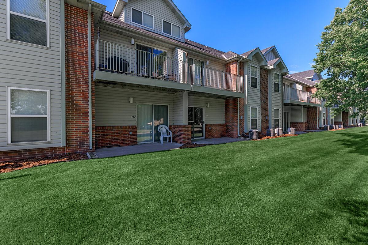 a large brick building with grass in front of a house