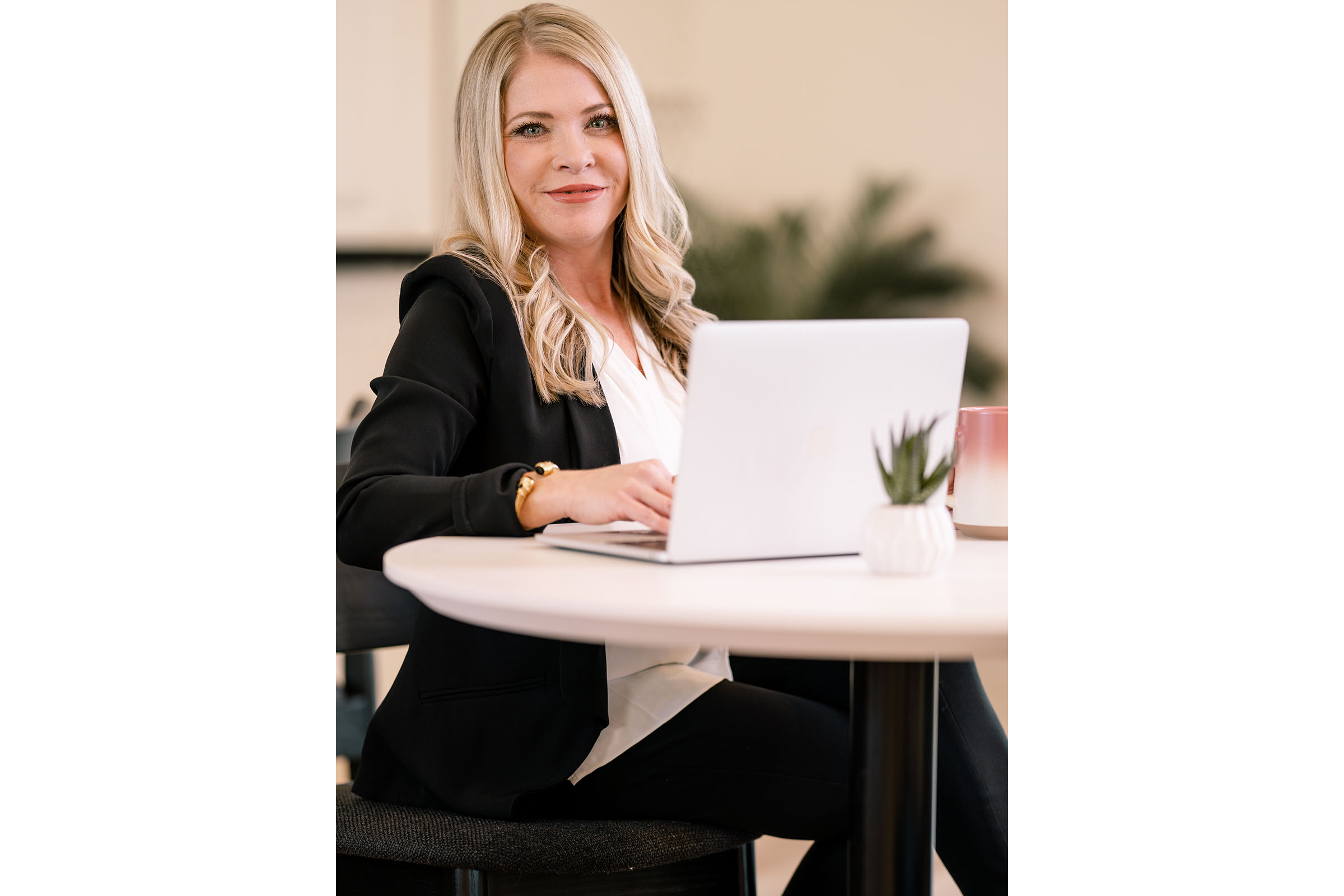 a woman sitting with a laptop and smiling at the camera