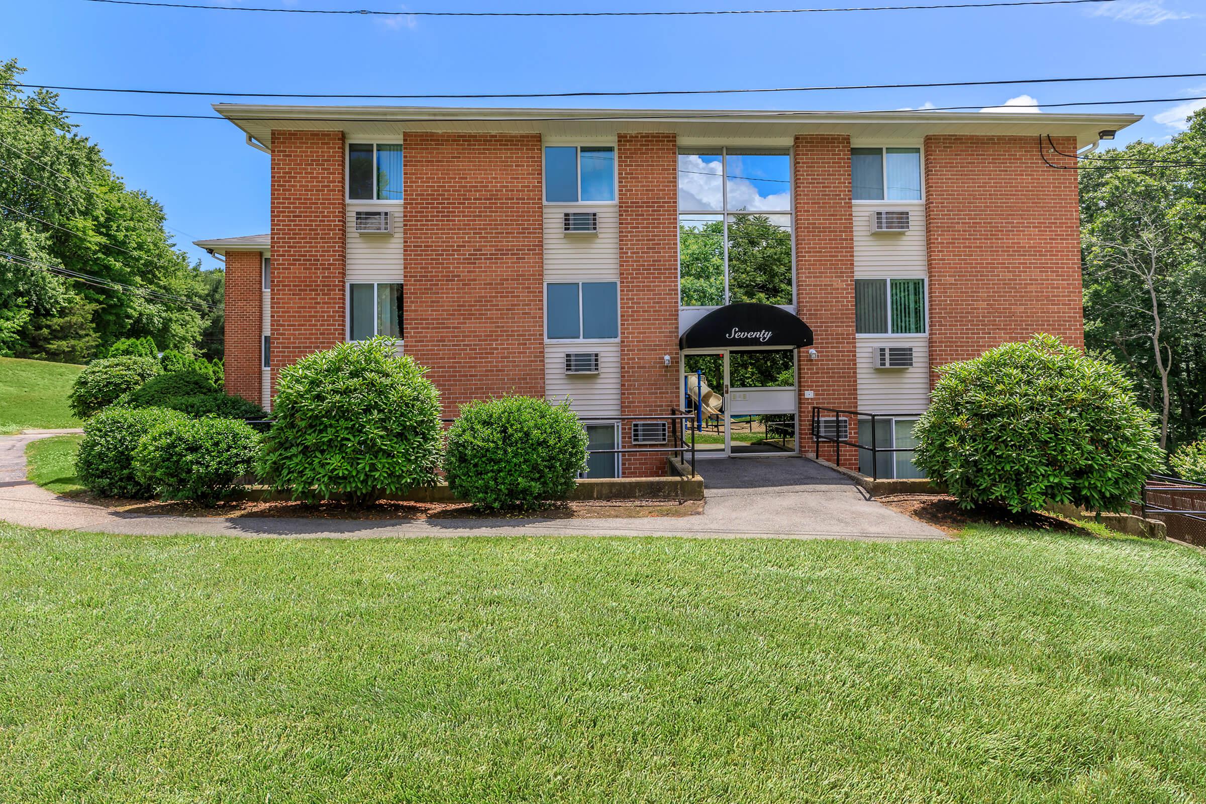 a large brick building with green grass