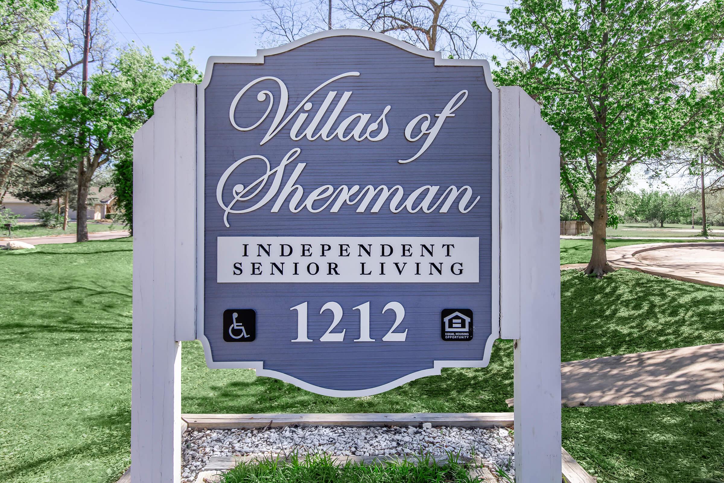 Sign for "Villas of Sherman," featuring the text "Independent Senior Living" along with the address "1212." The sign is surrounded by green grass and trees, indicating a pleasant outdoor setting. A wheelchair accessibility symbol and a house icon are also present, suggesting amenities for residents.