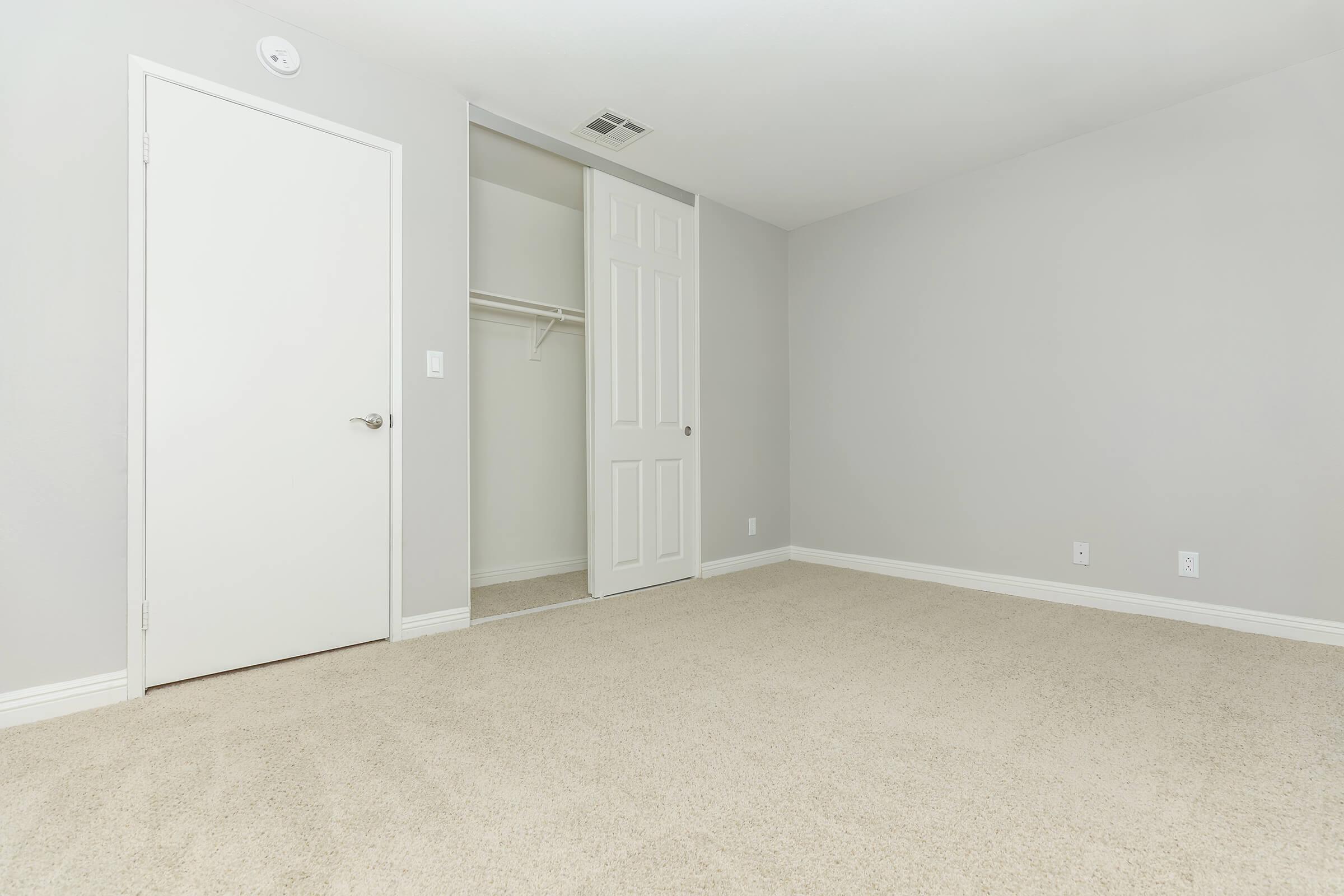 Vacant carpeted bedroom with sliding closet doors