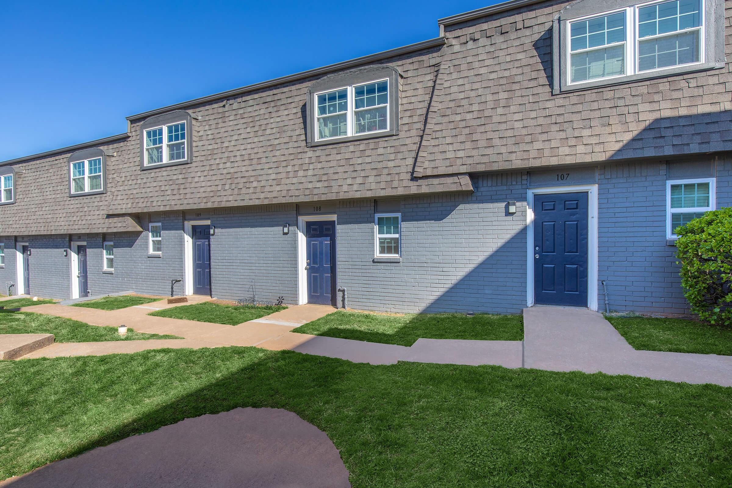 a large brick building with grass in front of a house