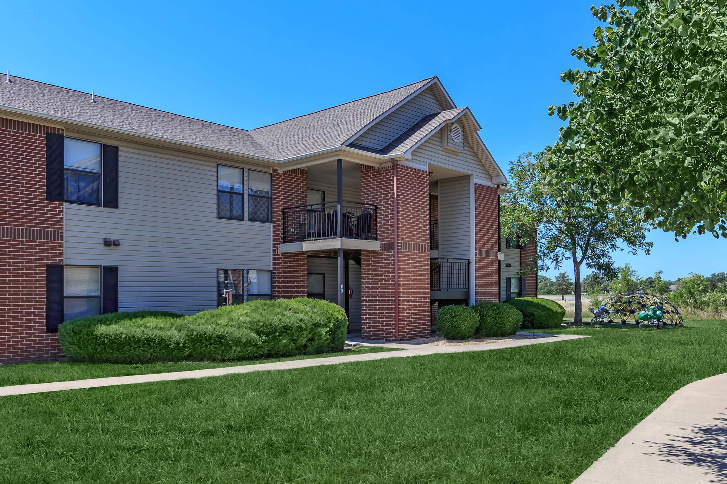 a house with a lawn in front of a brick building