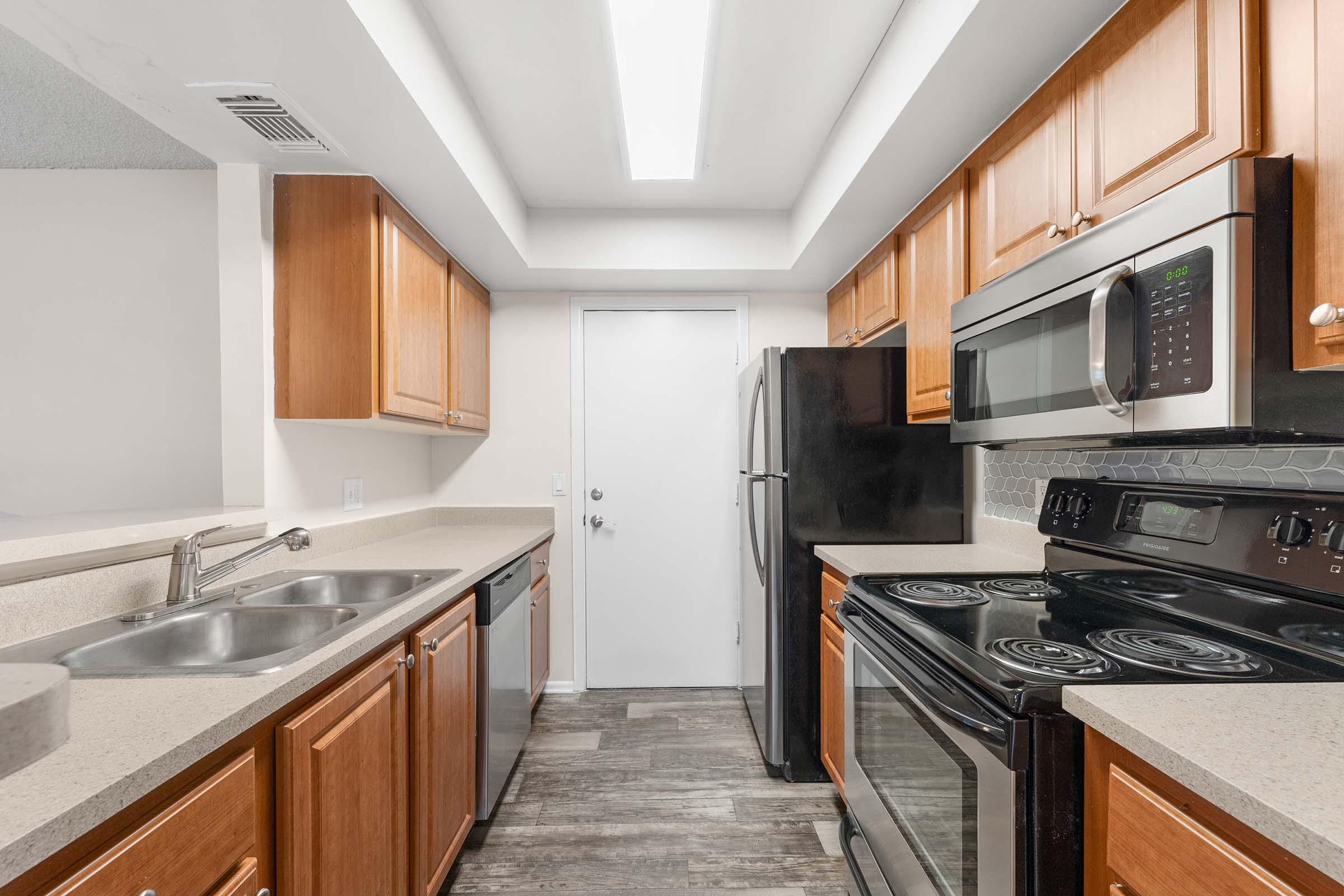 a large kitchen with stainless steel appliances and wooden cabinets