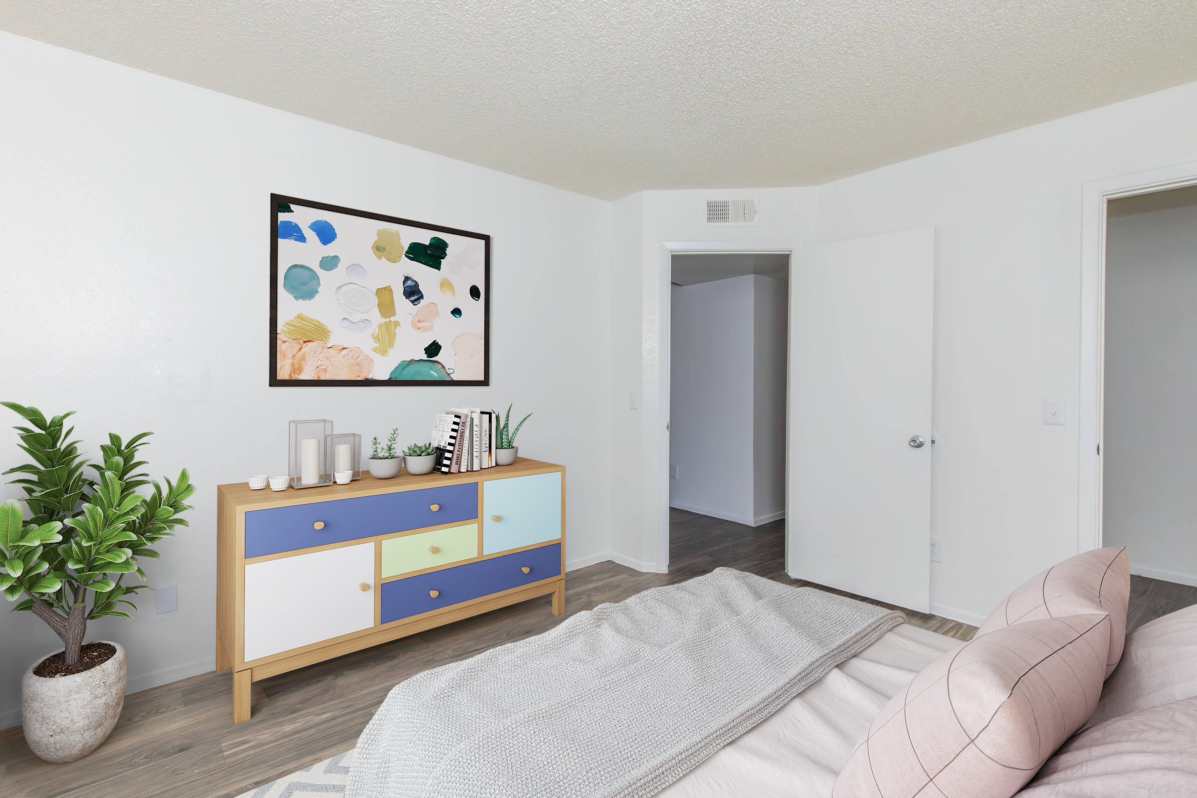 A modern bedroom featuring a cozy bed with light gray bedding, a stylish dresser with blue and white accents, a decorative plant, and a colorful abstract painting on the wall. The room has a bright, airy feel with neutral-colored walls and wooden flooring, along with an open door leading to another room.