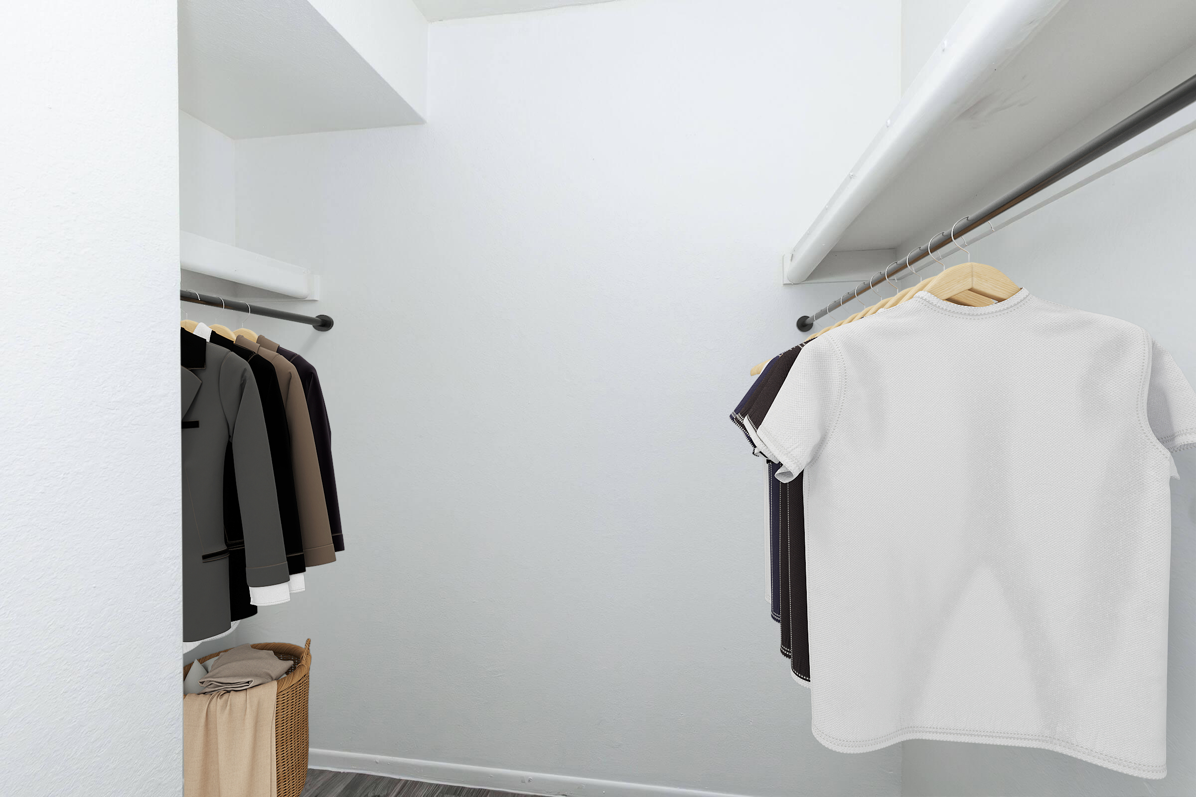 A spacious closet interior featuring a hanging rod with neatly arranged shirts in various colors. A laundry basket is positioned on the floor, and the walls are painted white, creating a bright and organized storage space for clothing.
