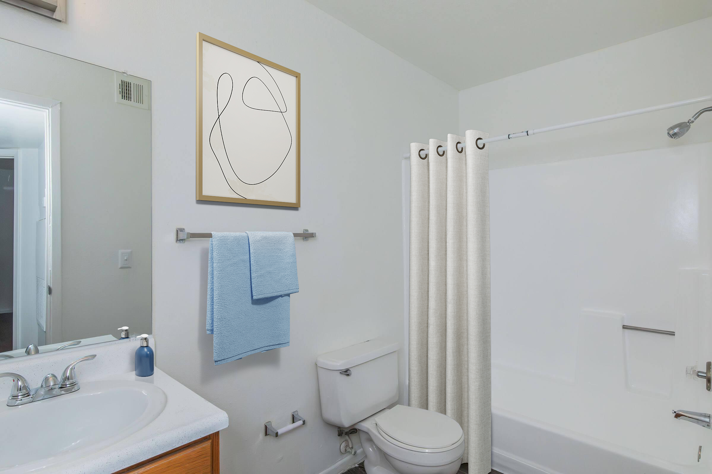 A clean and modern bathroom featuring a white bathtub and shower, a toilet, a sink with chrome fixtures, and a wooden vanity. There is a large mirror, a blue towel hanging on a rack, a light-colored shower curtain, and an abstract art piece on the wall.