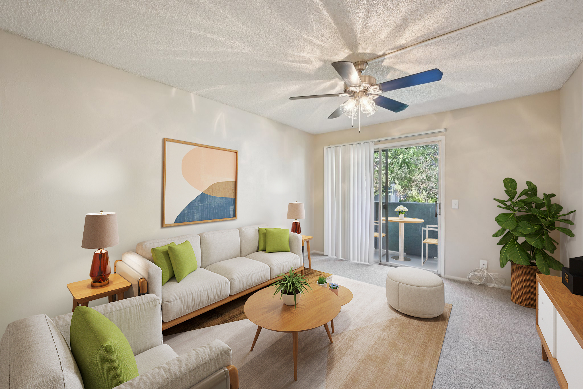 A cozy living room featuring a light-colored sofa with green accent pillows, a round wooden coffee table, and an ottoman. There are two lamps on side tables, a large wall art piece, and a plant in the corner. Natural light streams in from a sliding glass door leading to a small balcony.