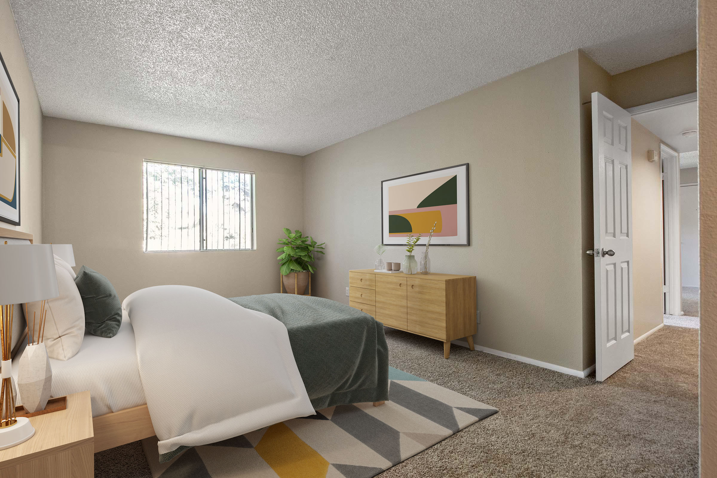 A cozy bedroom featuring a bed with white bedding and a dark green throw blanket. There is a wooden side table with a lamp, a large window allowing natural light, and a potted plant. The walls are painted in a light beige, and a modern artwork hangs above a wooden dresser. A door leads to another room.