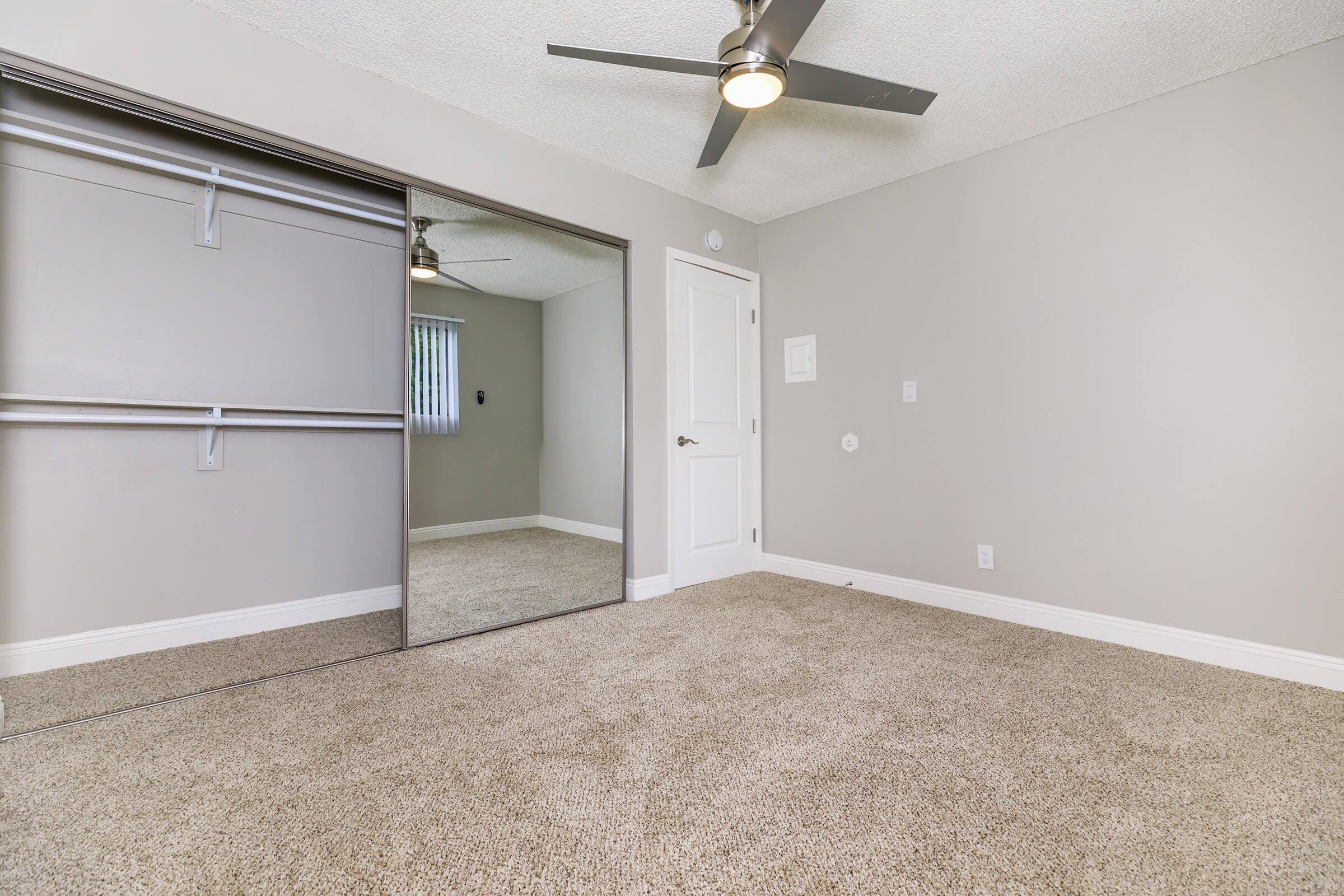 Carpeted bedroom with open sliding mirror closet doors