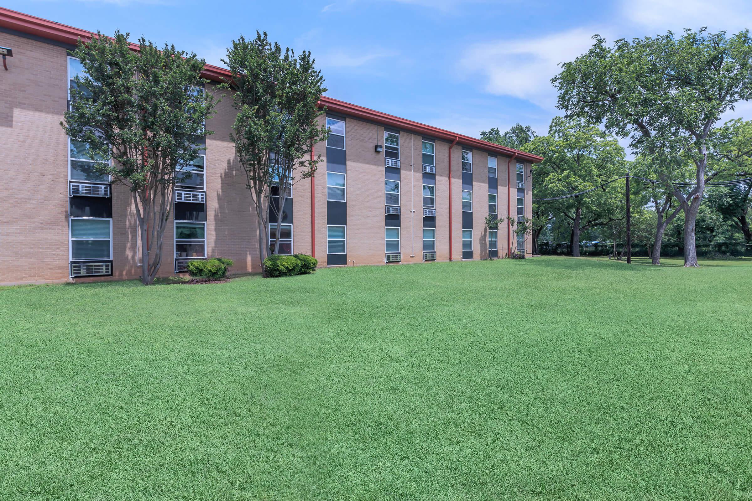 a large brick building with green grass