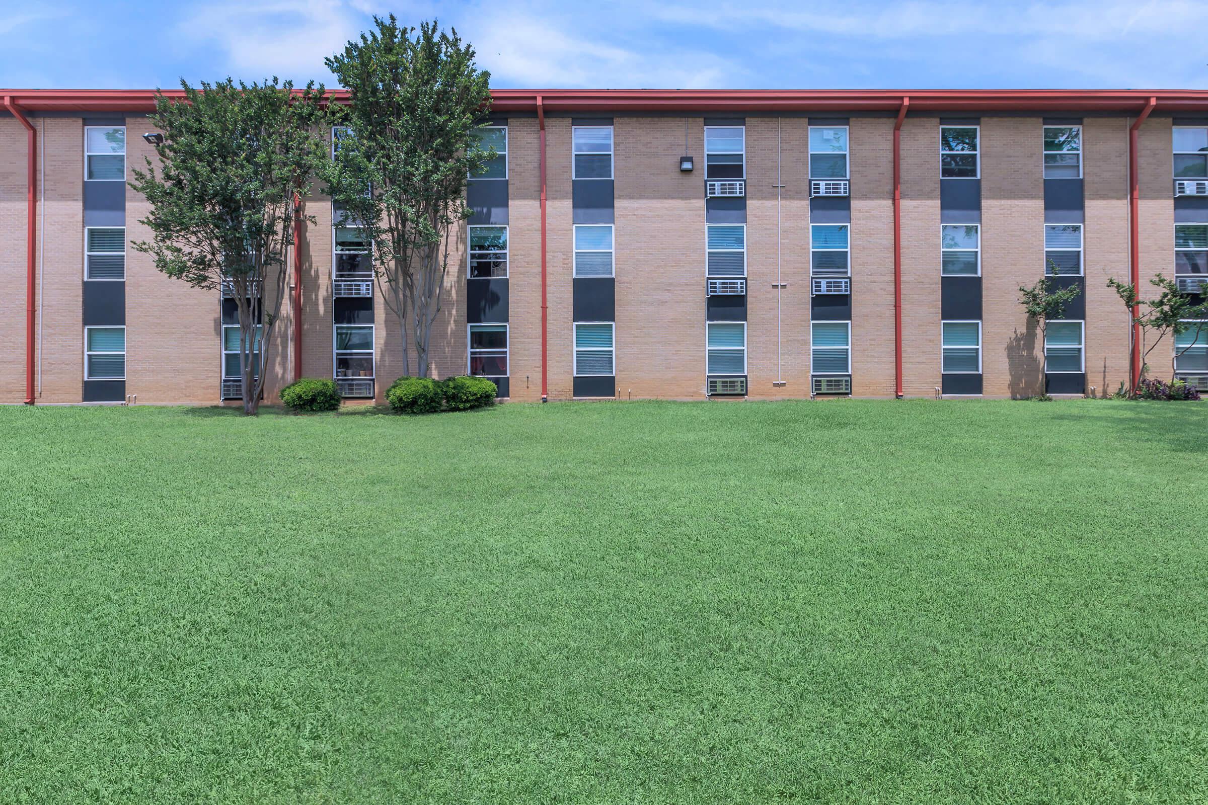 a large green field in front of a building