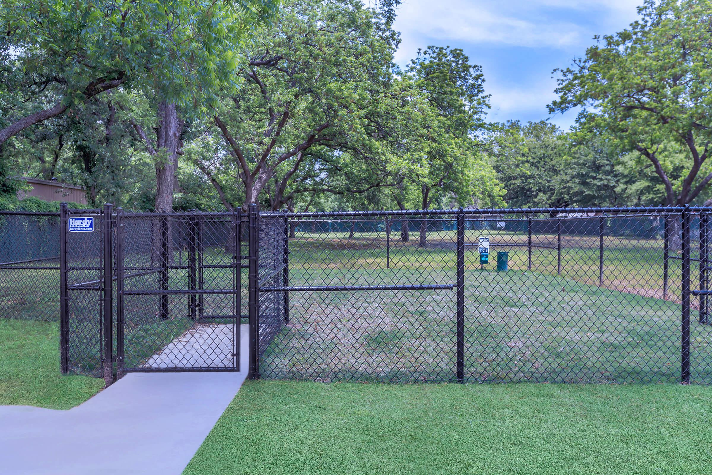 a fenced in grassy area with trees in the background
