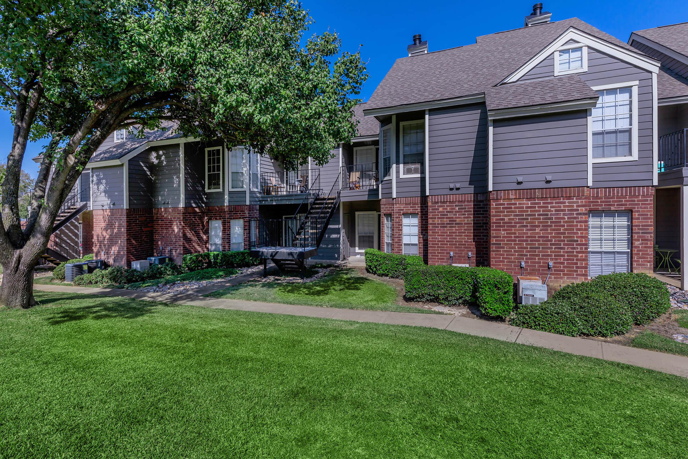 a house with a lawn in front of a brick building