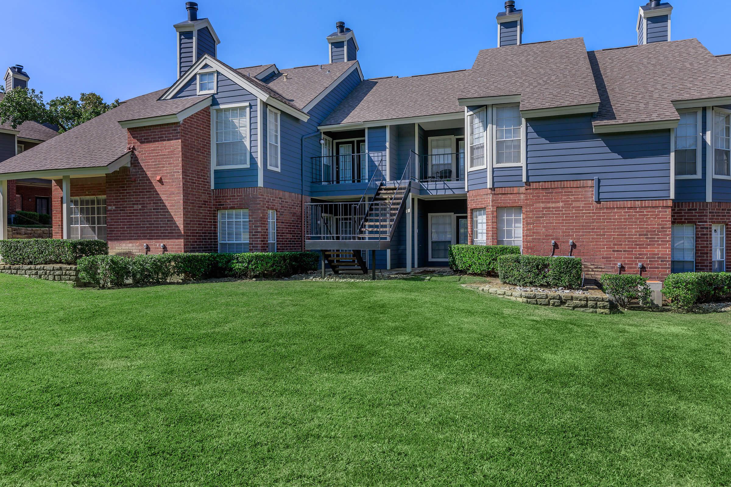 a large brick building with green grass in front of a house