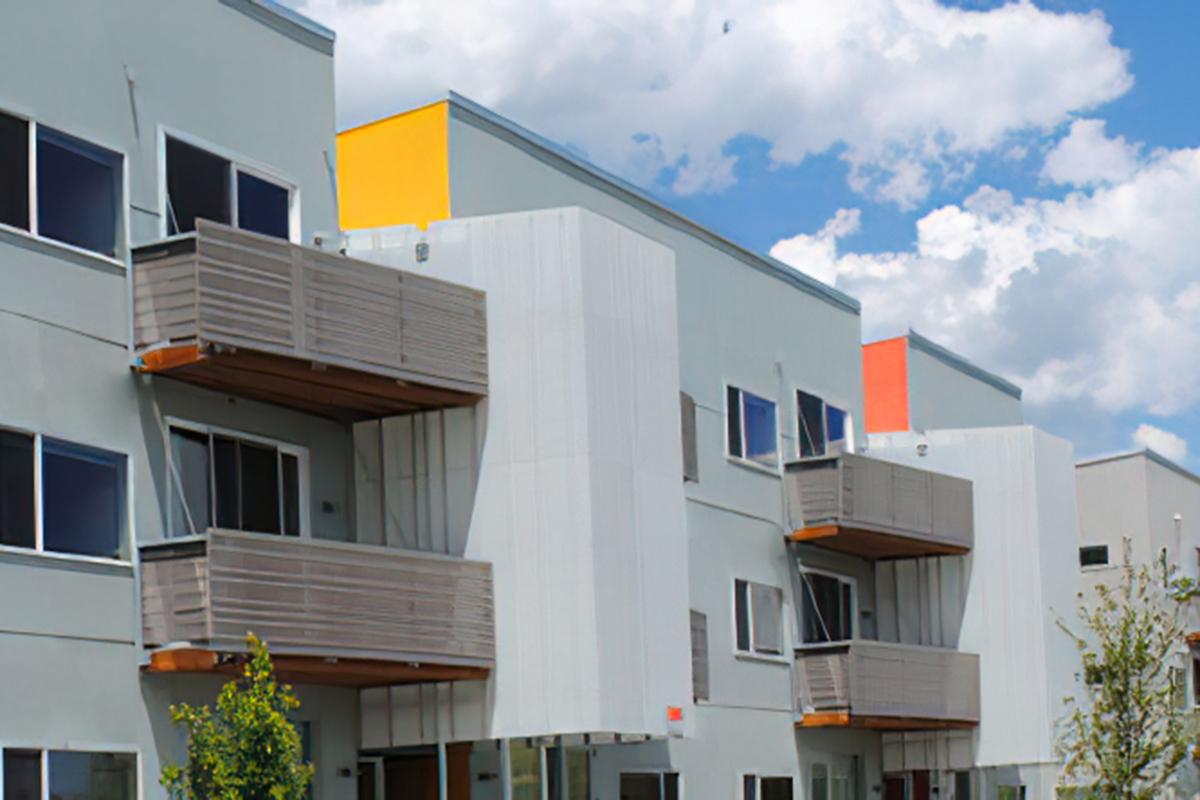 A modern apartment building featuring several grey facades with wooden balconies.