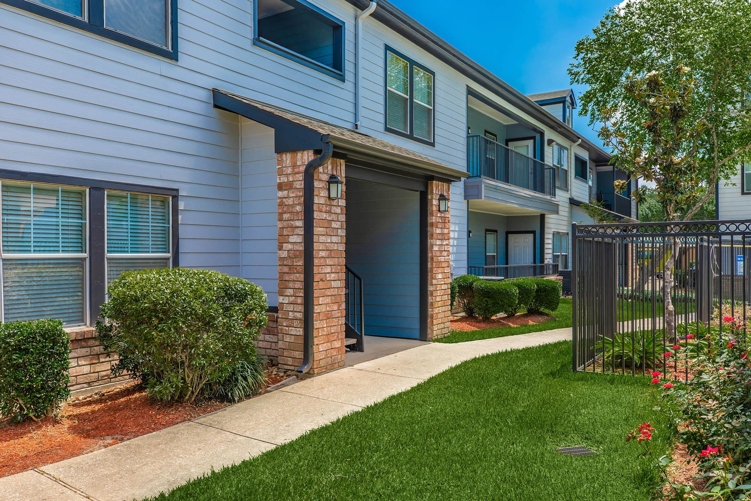 a house with bushes in front of a brick building