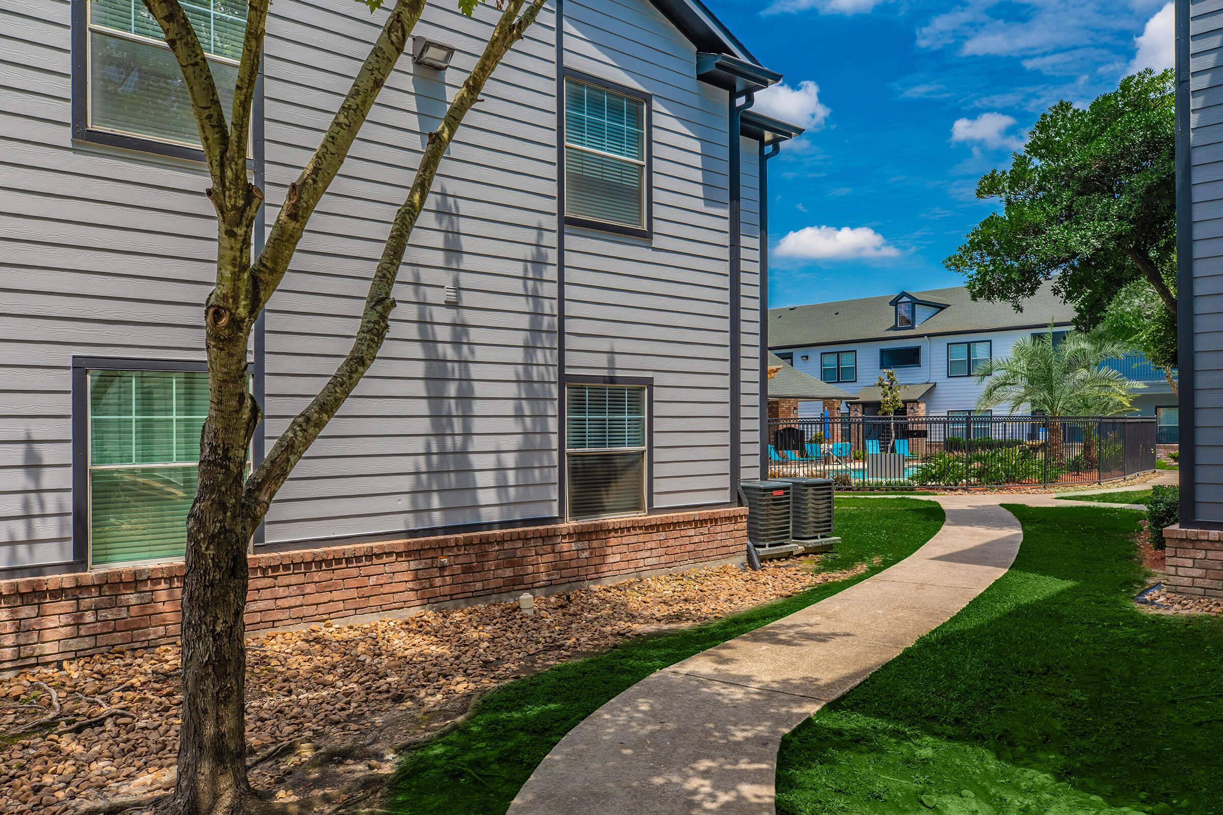 a large brick building with grass in front of a house