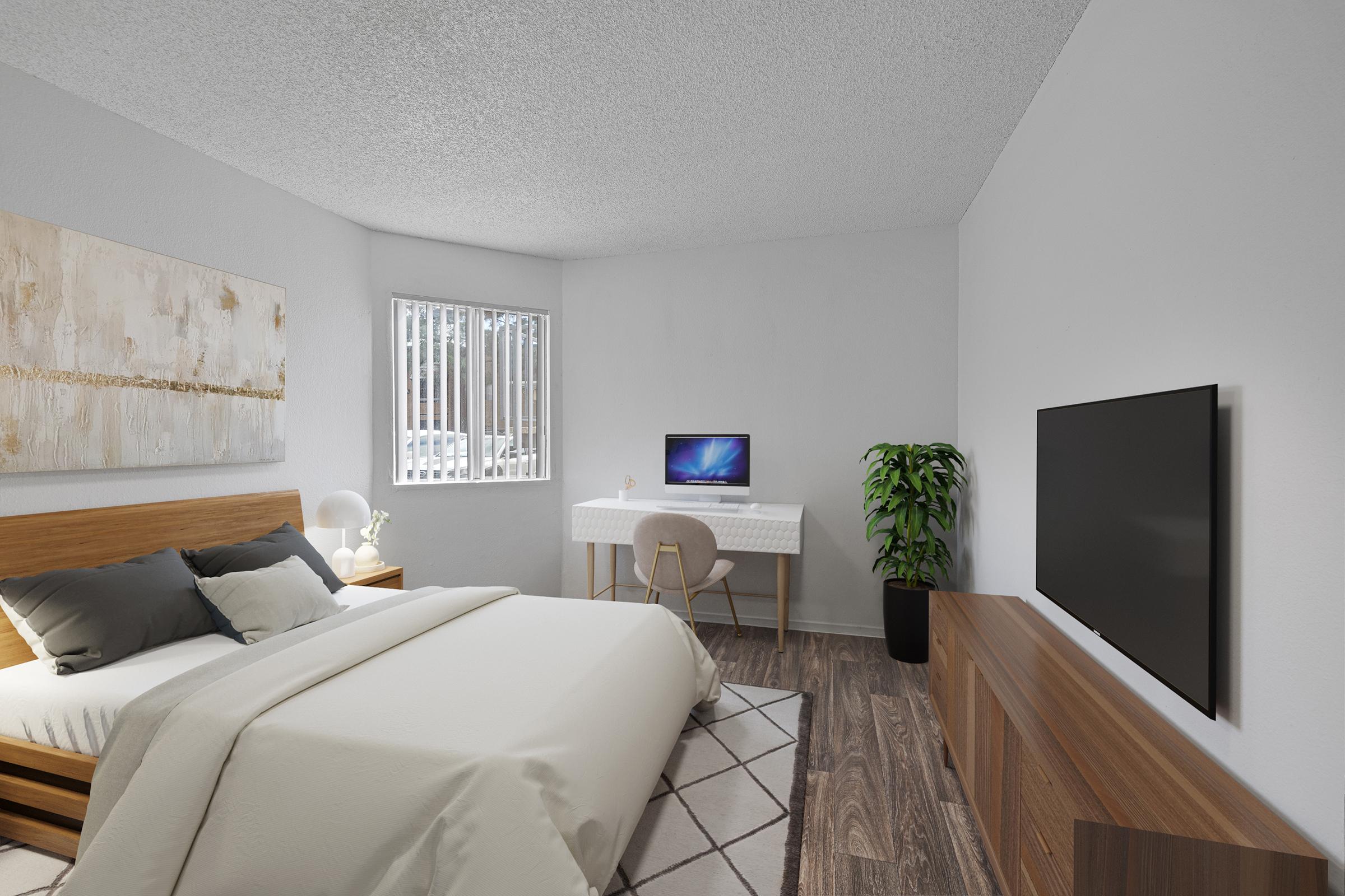 A modern bedroom featuring a bed with light bedding, a wall-mounted TV, a desk with a computer, and a decorative plant. The walls are painted in soft colors, and there’s a large window with grid-patterned blinds, allowing natural light to brighten the space. The floor has a wood-like finish.