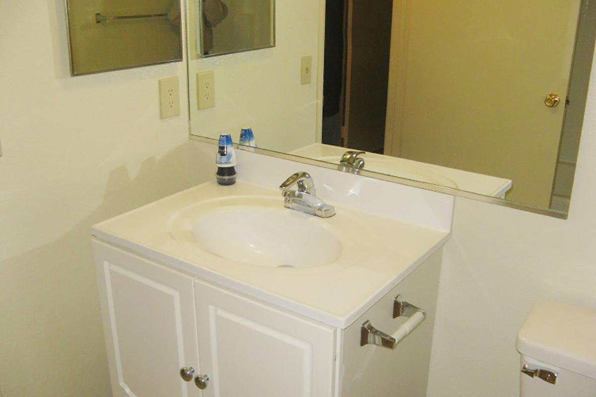 a white sink sitting under a mirror