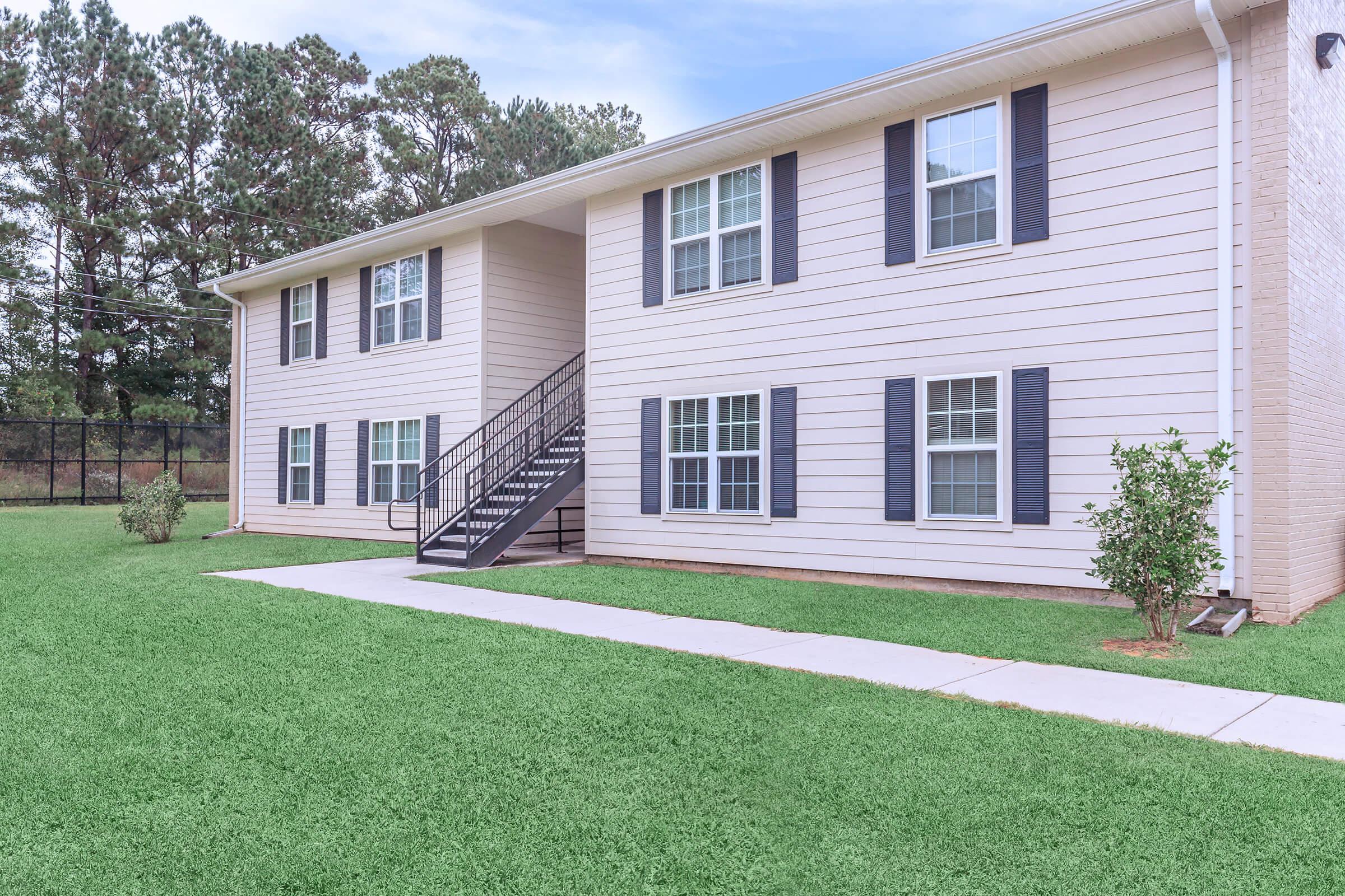 a house with a lawn in front of a brick building