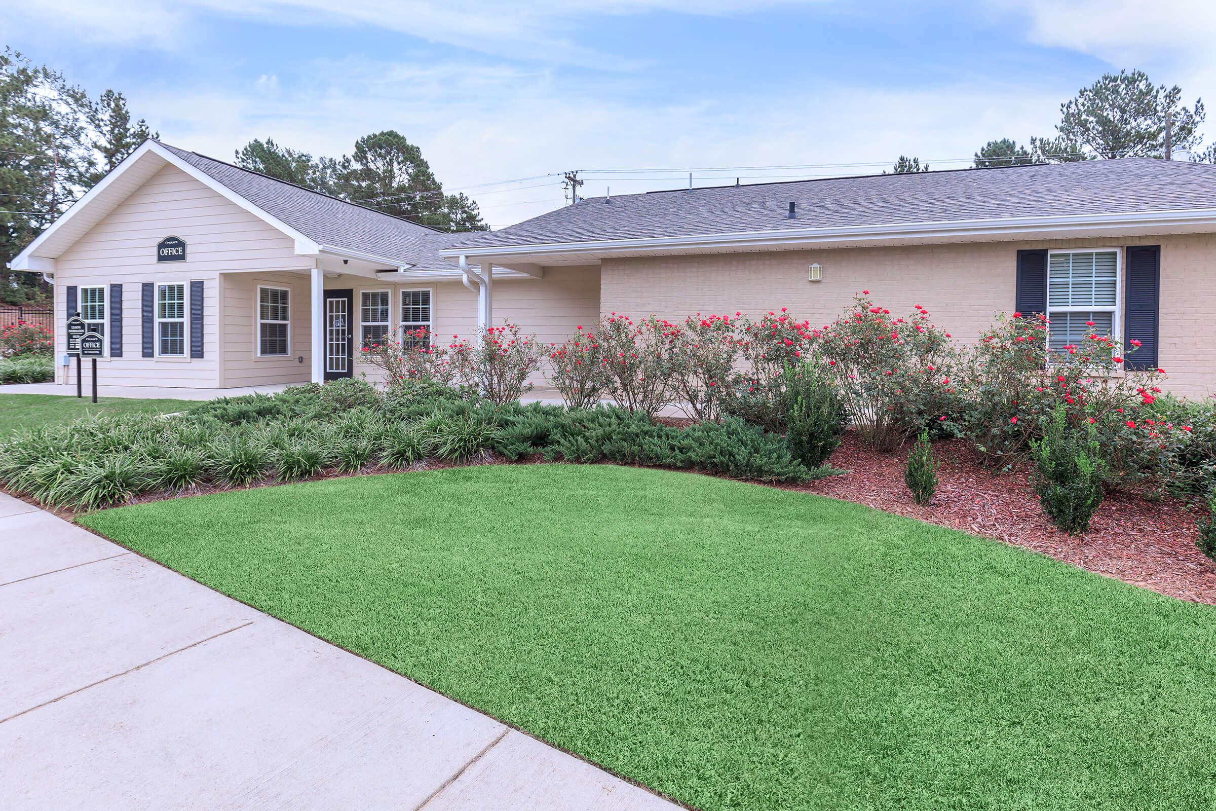 a large brick building with green grass in front of a house