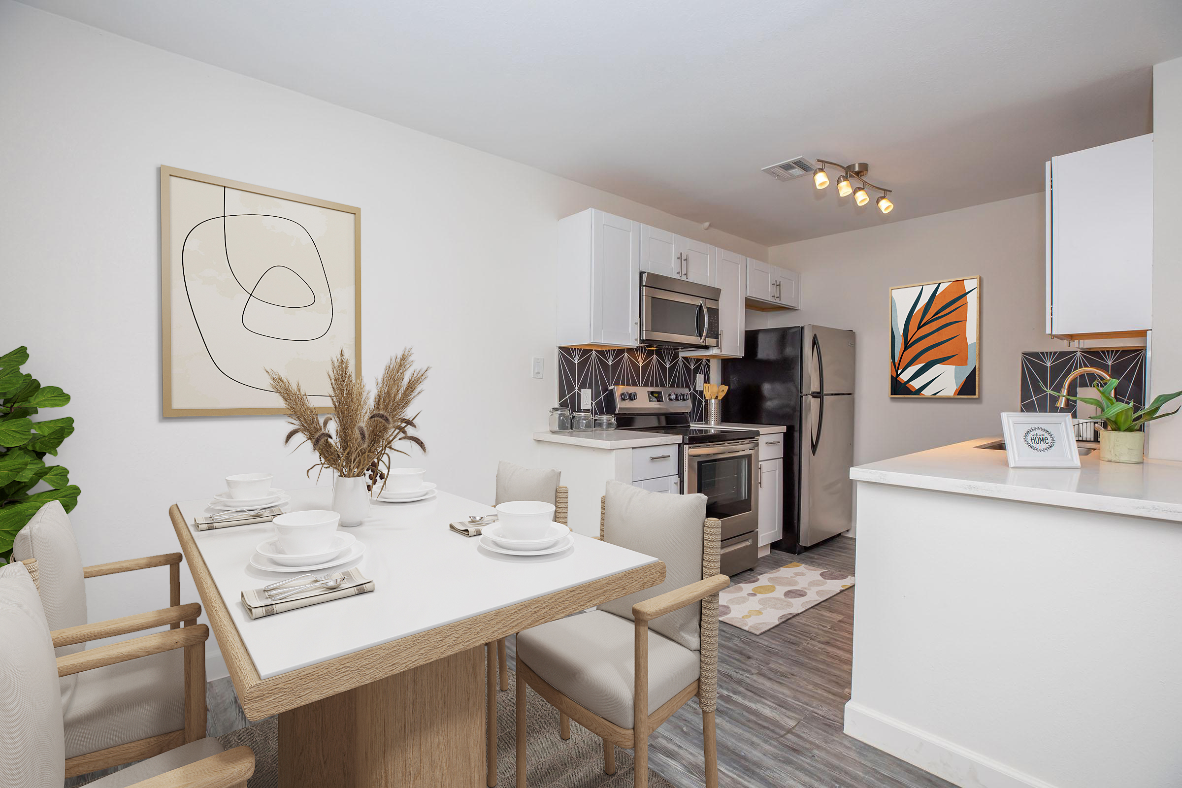 A modern kitchen and dining area featuring a wooden dining table set with plates and cutlery. The kitchen has white cabinets, stainless steel appliances, and decorative art on the walls. A small plant adds a touch of greenery to the space. Soft lighting creates a warm, inviting atmosphere.