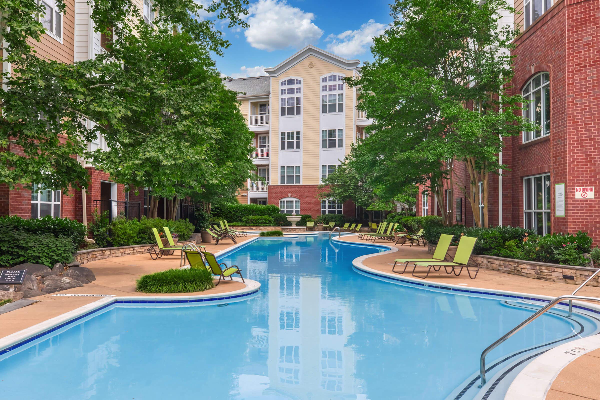 Images of a peaceful swimming pool area surrounded by greenery and modern buildings. The pool features clear blue water, comfortable lounge chairs, and is framed by trees and bushes, creating a relaxing outdoor environment. The sky is partly cloudy, adding to the serene atmosphere.