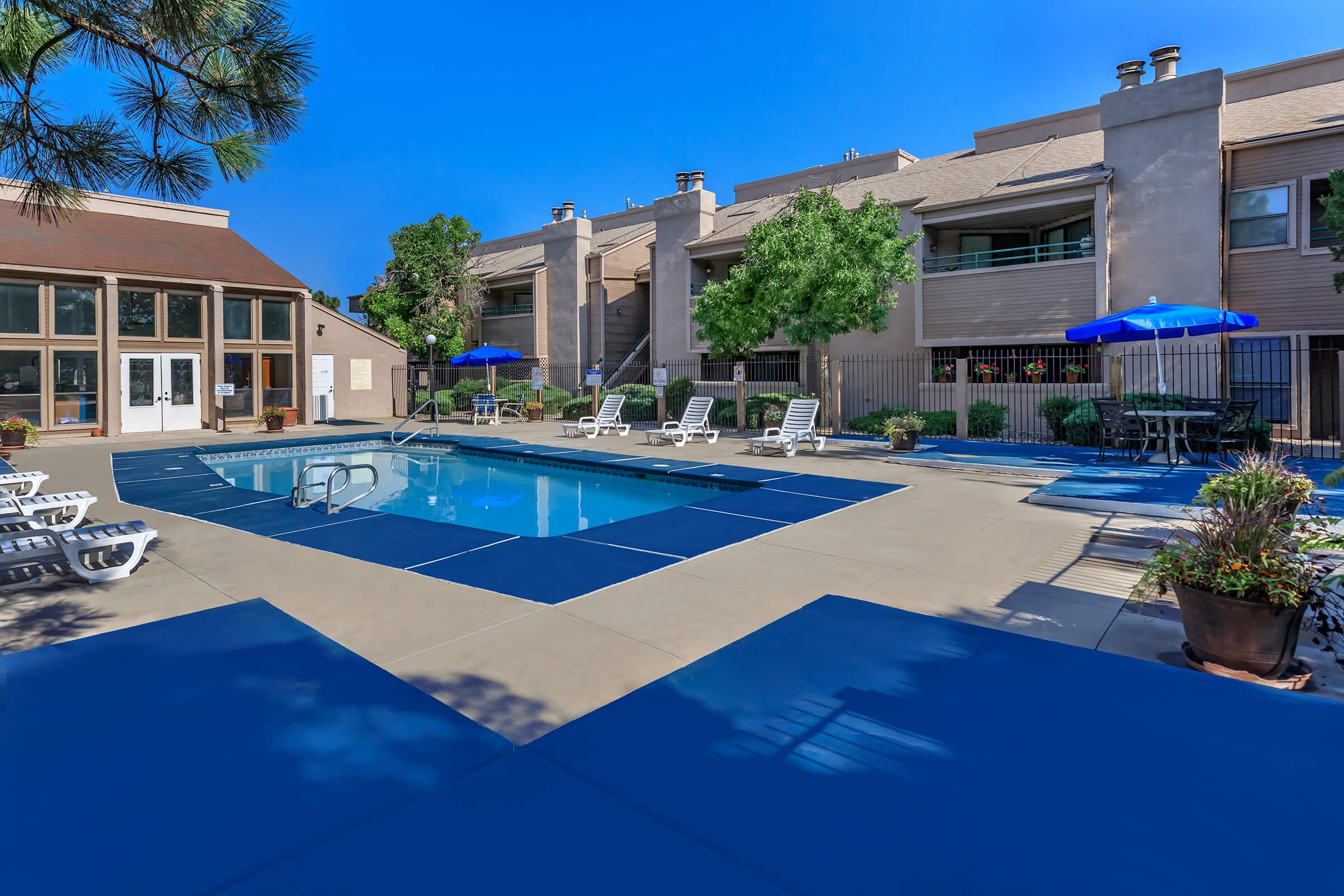 a community pool with blue umbrellas