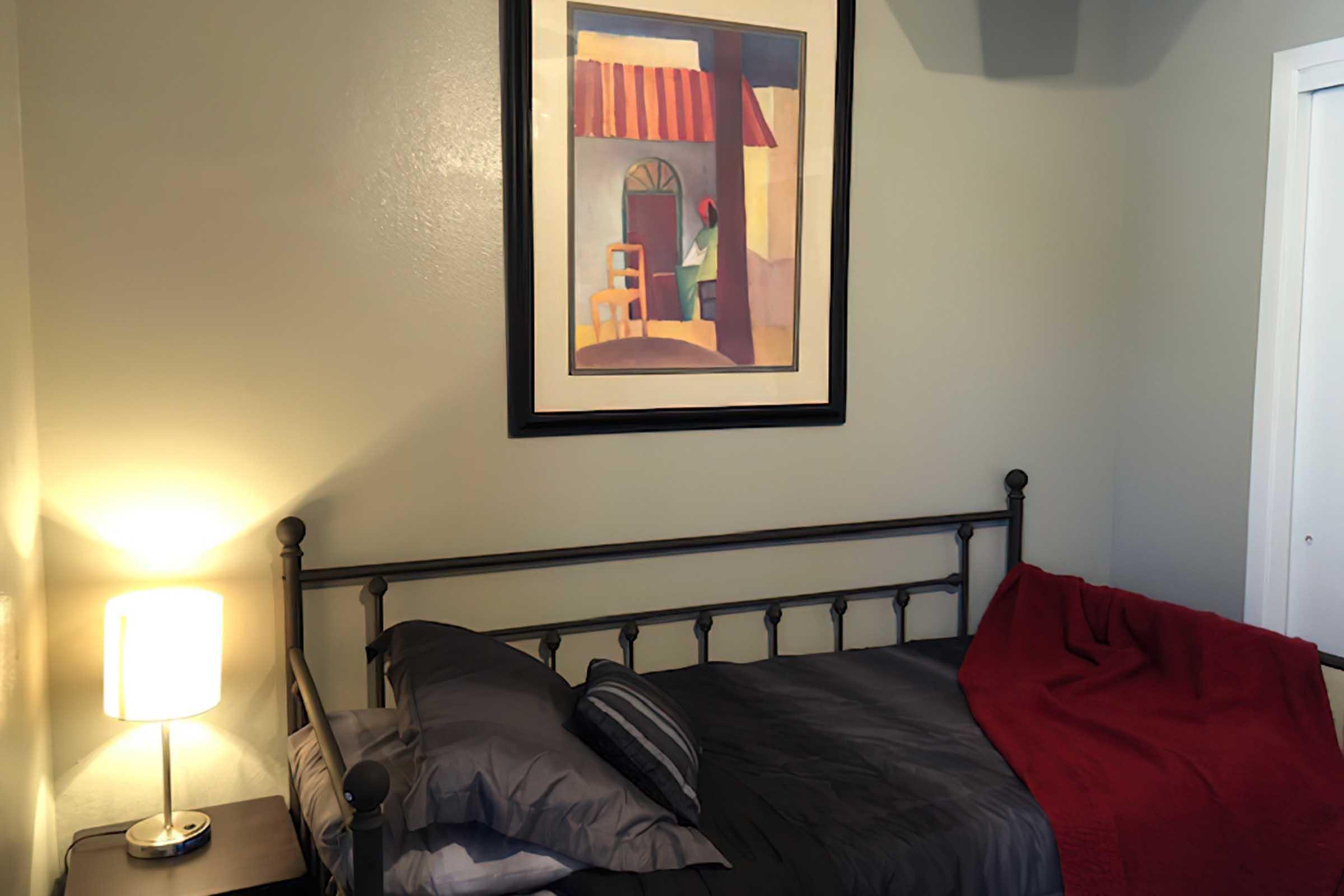 a bedroom with a bed and a painting on the wall