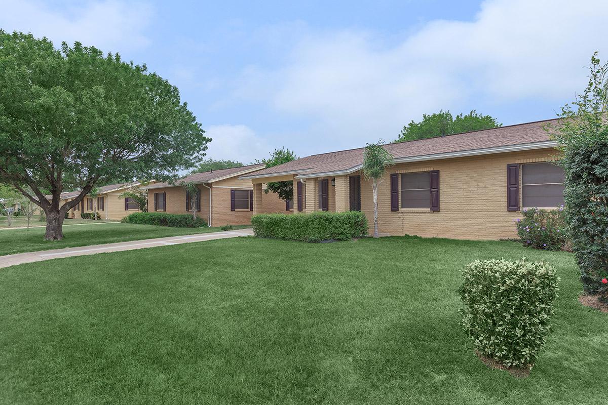 a large brick building with grass in front of a house