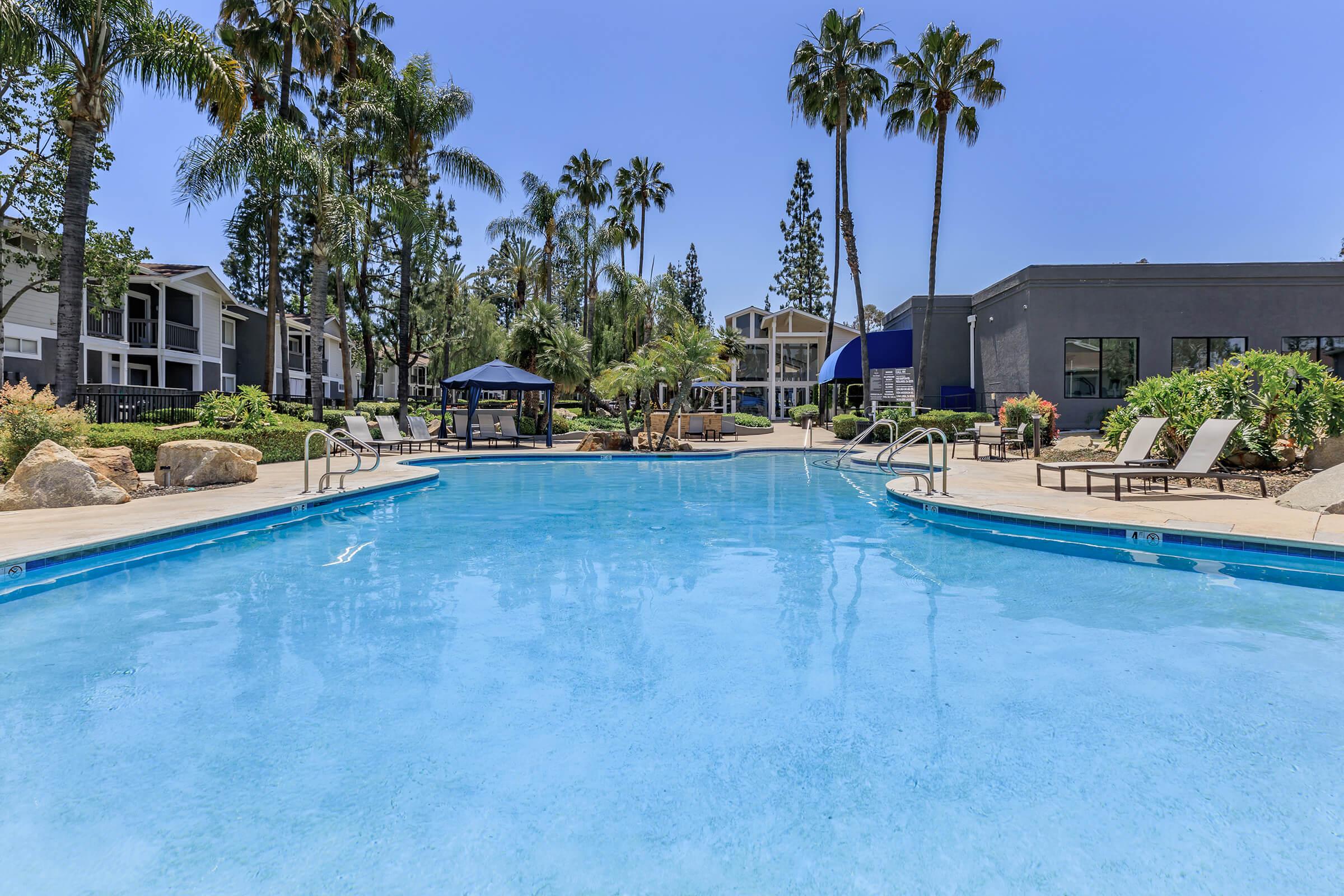 Apartments in Redlands, CA - Redlands Lawn and Tennis - Swimming Pool with Lounge Seating, a Spa, and Lush Landscaping