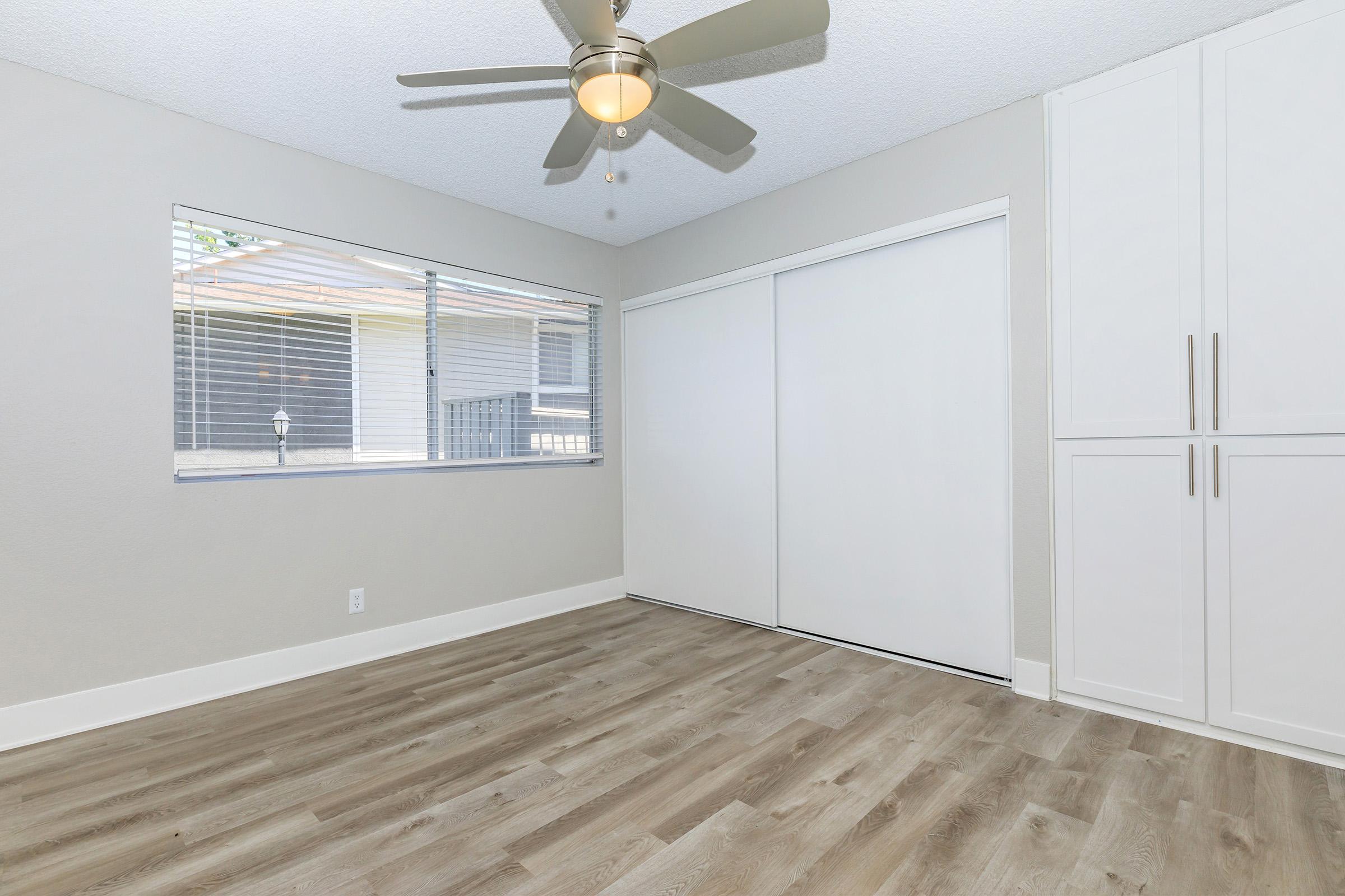 Two-Bedroom Apartments in Redlands, CA - Redlands Lawn and Tennis - Bedroom with a Large Window, a Ceiling Fan, and an Oversized Closet