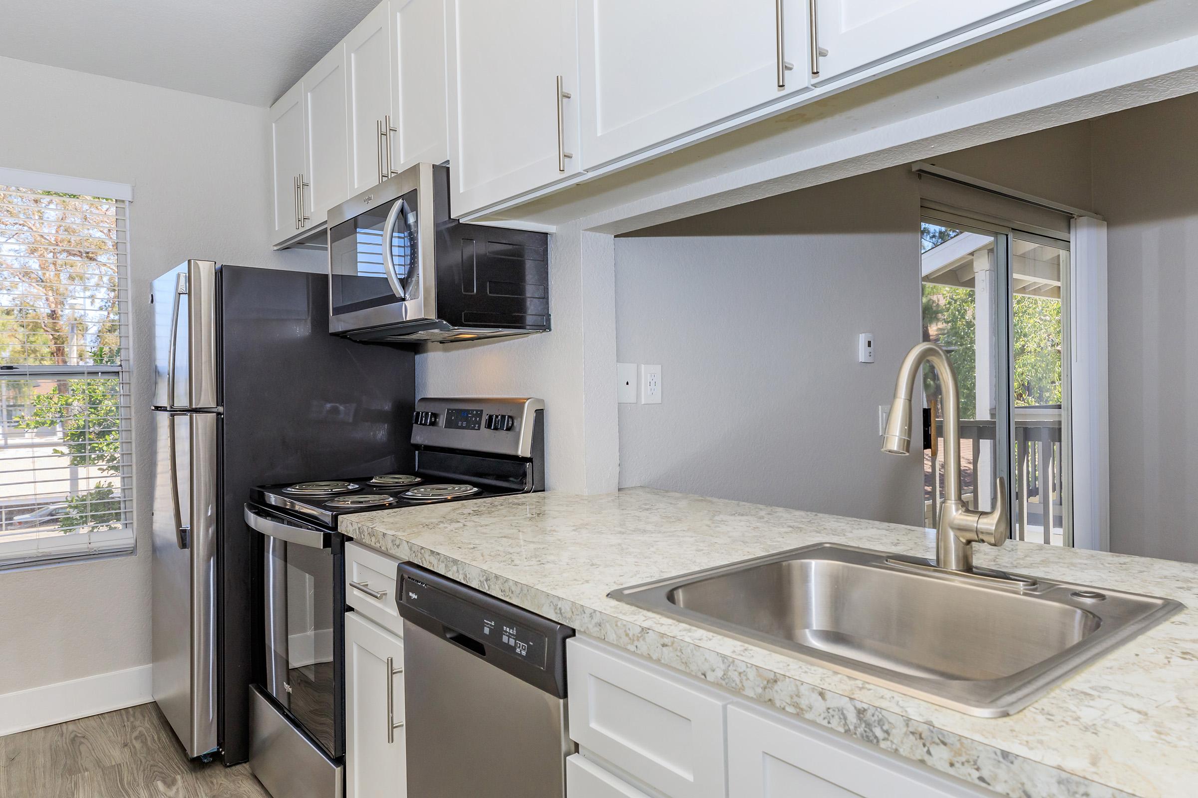 Redlands, CA Apartments with In-Unit Washer and Dryer - Redlands Lawn and Tennis - Kitchen with Stainless Steel Appliances, White Cabinets, and Chrome Hardware