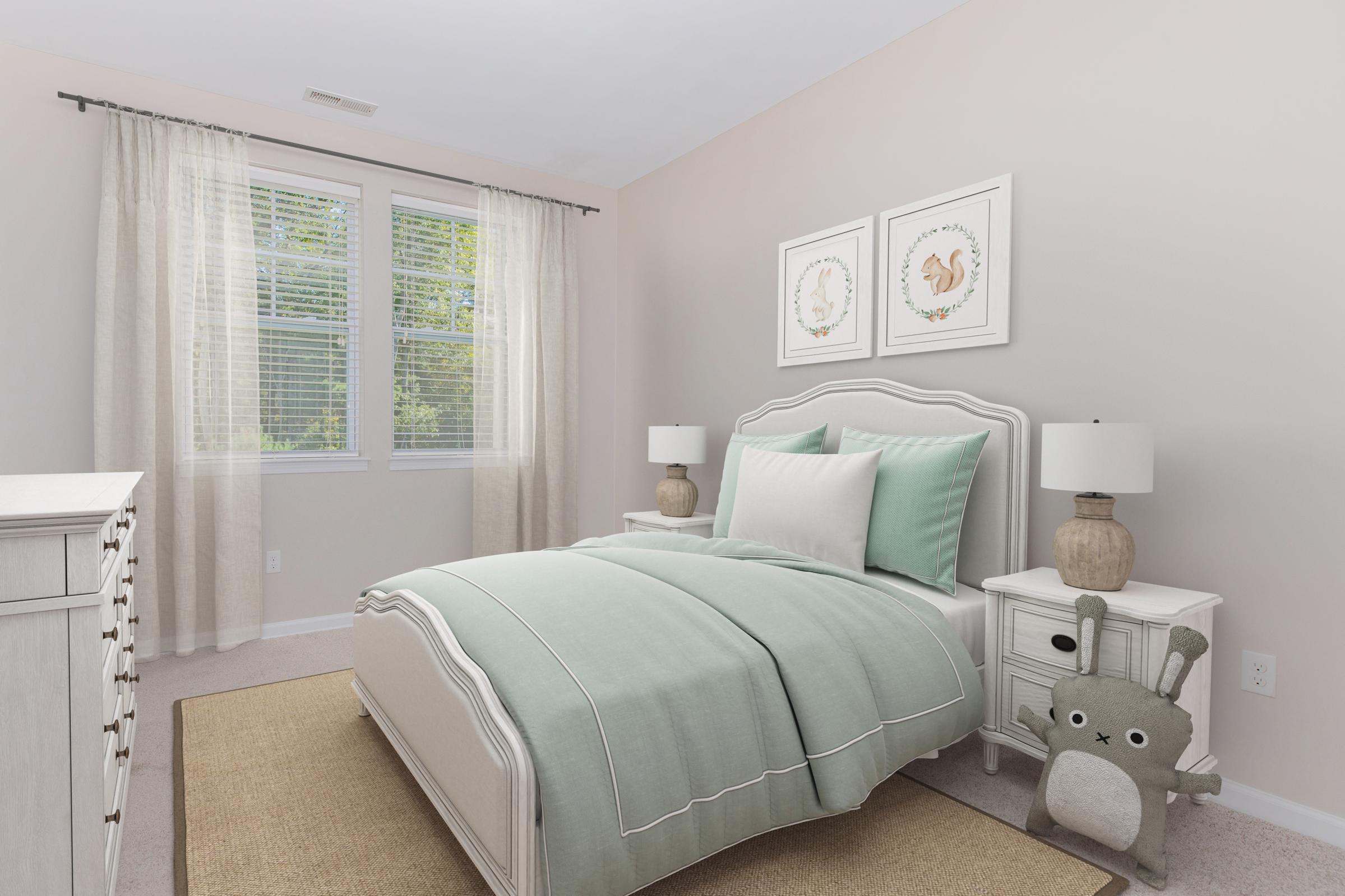 A cozy, softly lit bedroom featuring a bed with a light mint green comforter and white linens. Two decorative lamps sit on nightstands beside the bed, and framed artwork adorns the wall. A plush toy resembling a small animal rests on the floor next to a light-colored rug. Large windows allow natural light to illuminate the room.