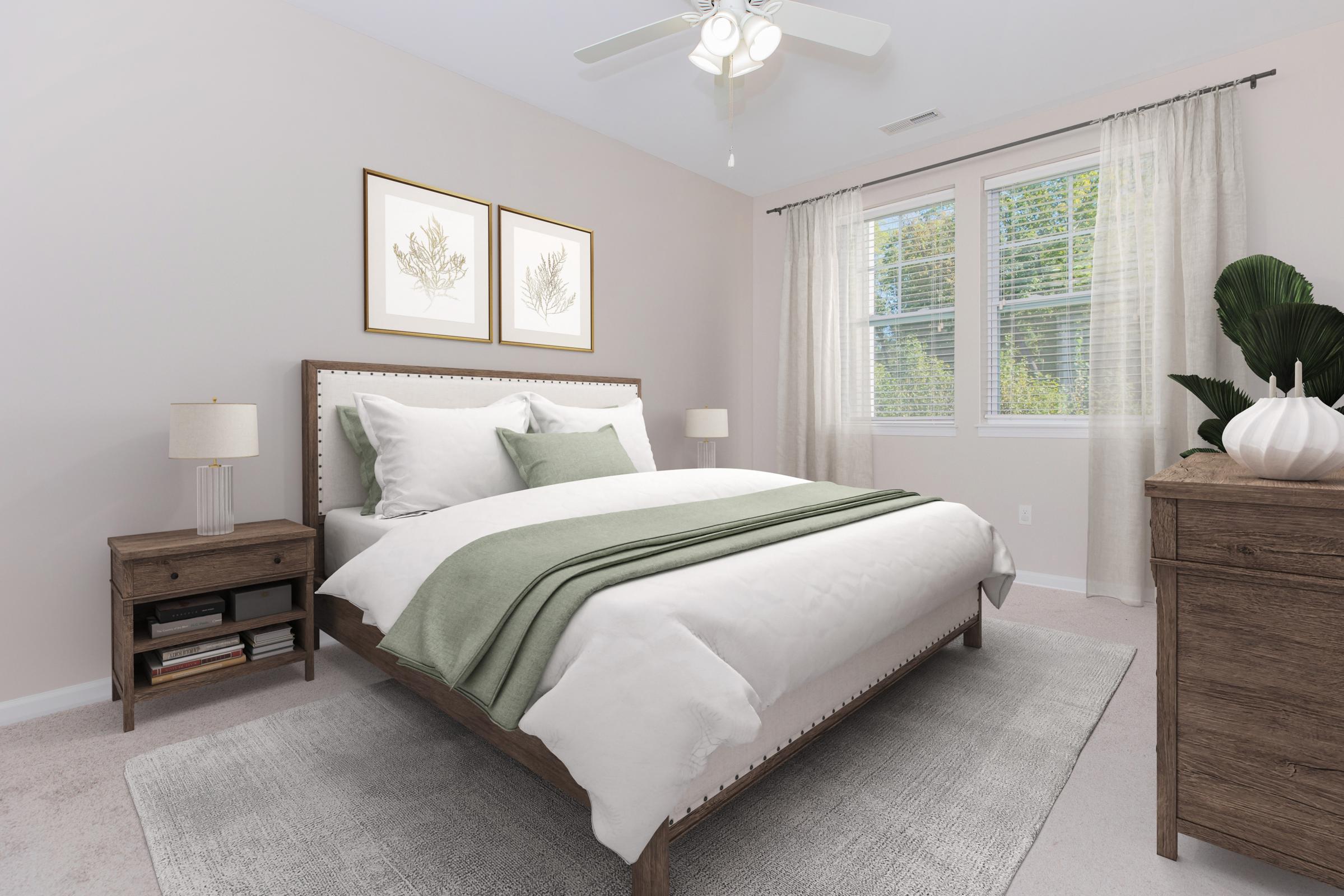 A cozy bedroom featuring a wooden bed with white bedding and a green throw blanket. There are two framed botanical prints on the wall, a bedside table with a lamp, and a dresser. Light curtains cover the windows, allowing natural light to brighten the space, which has a neutral color palette and soft carpet.