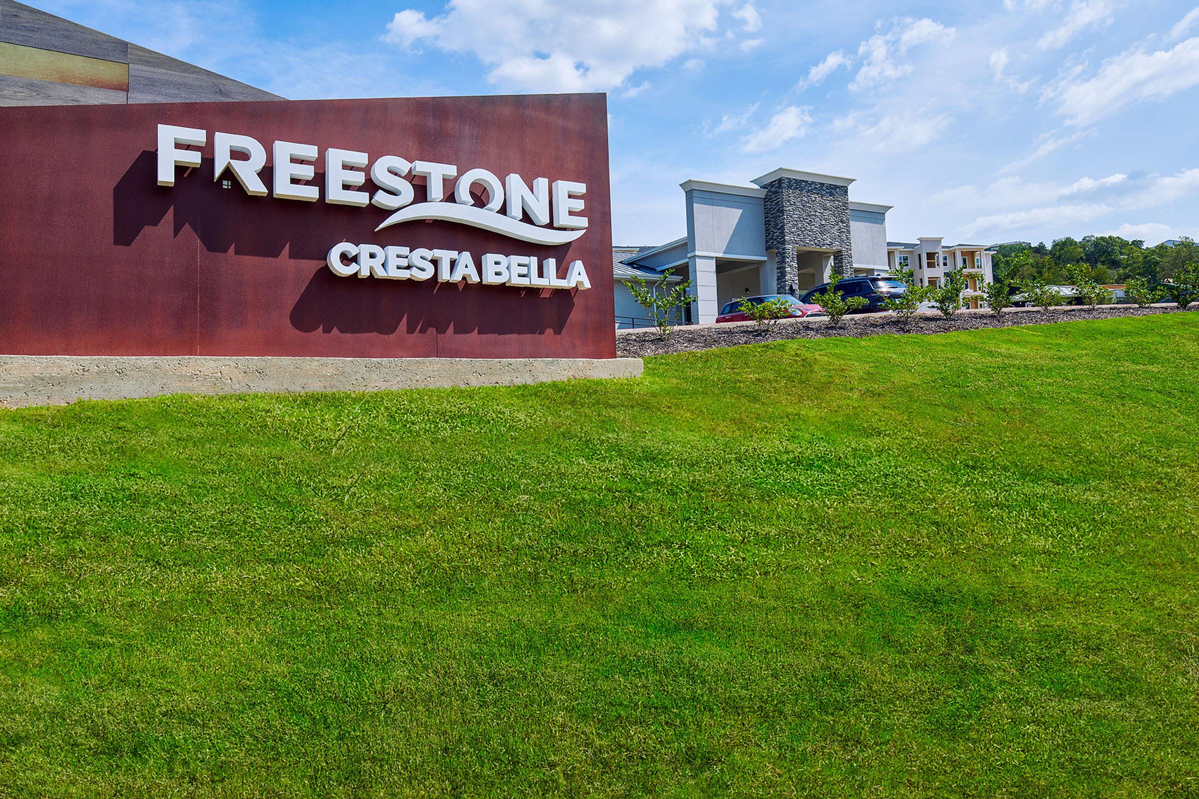 a sign above a grassy field