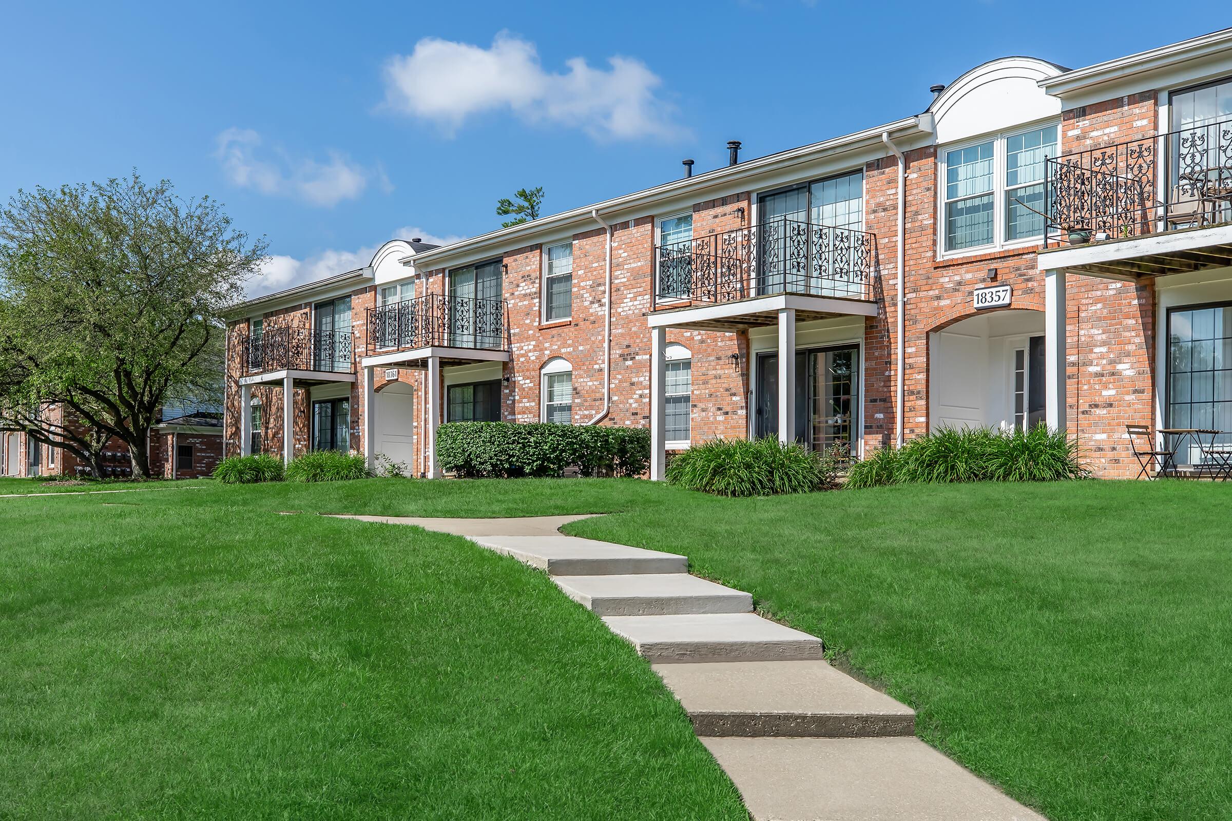 a large brick building with grass in front of a house