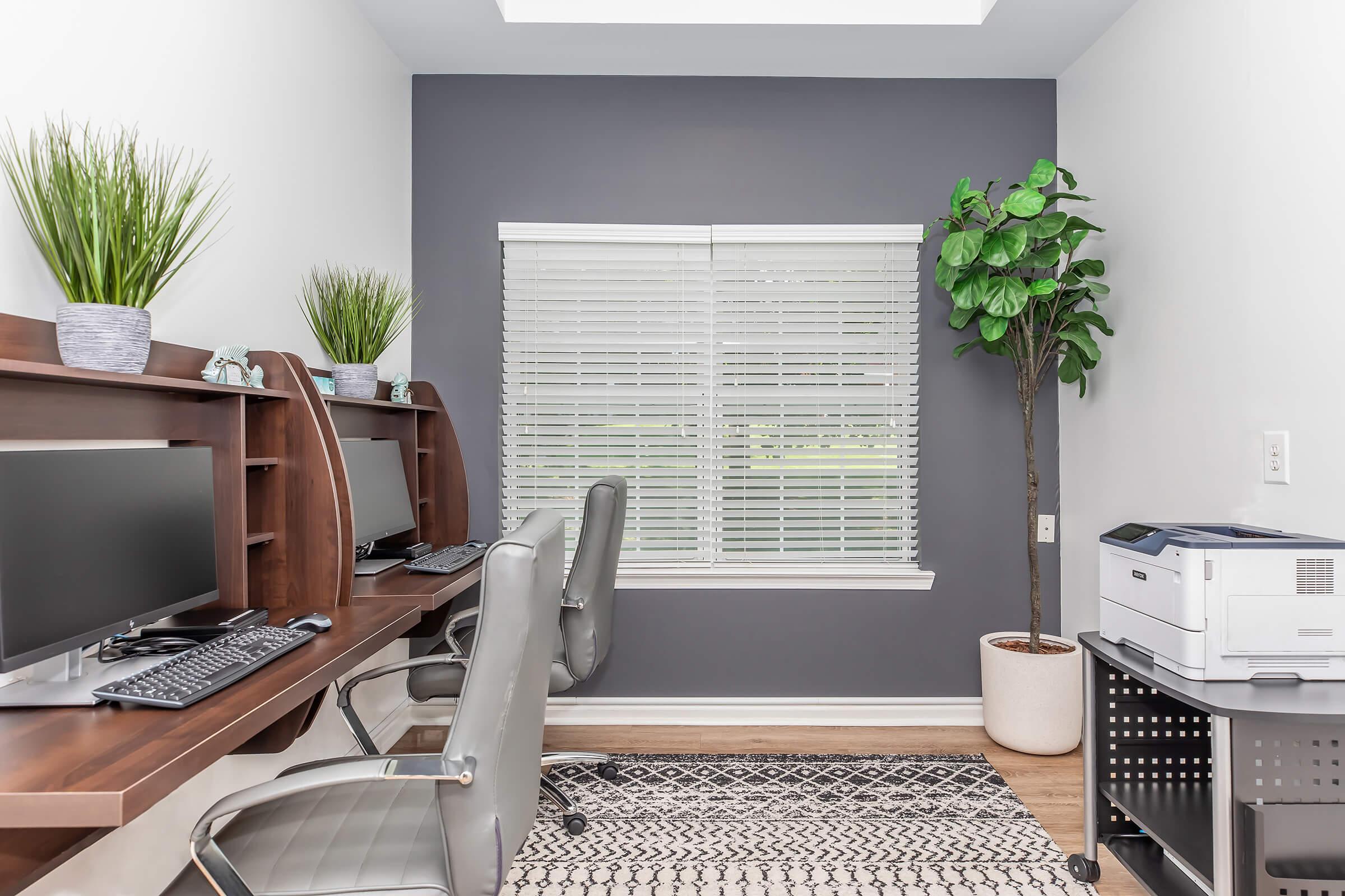 a desk with a computer and a chair in a room