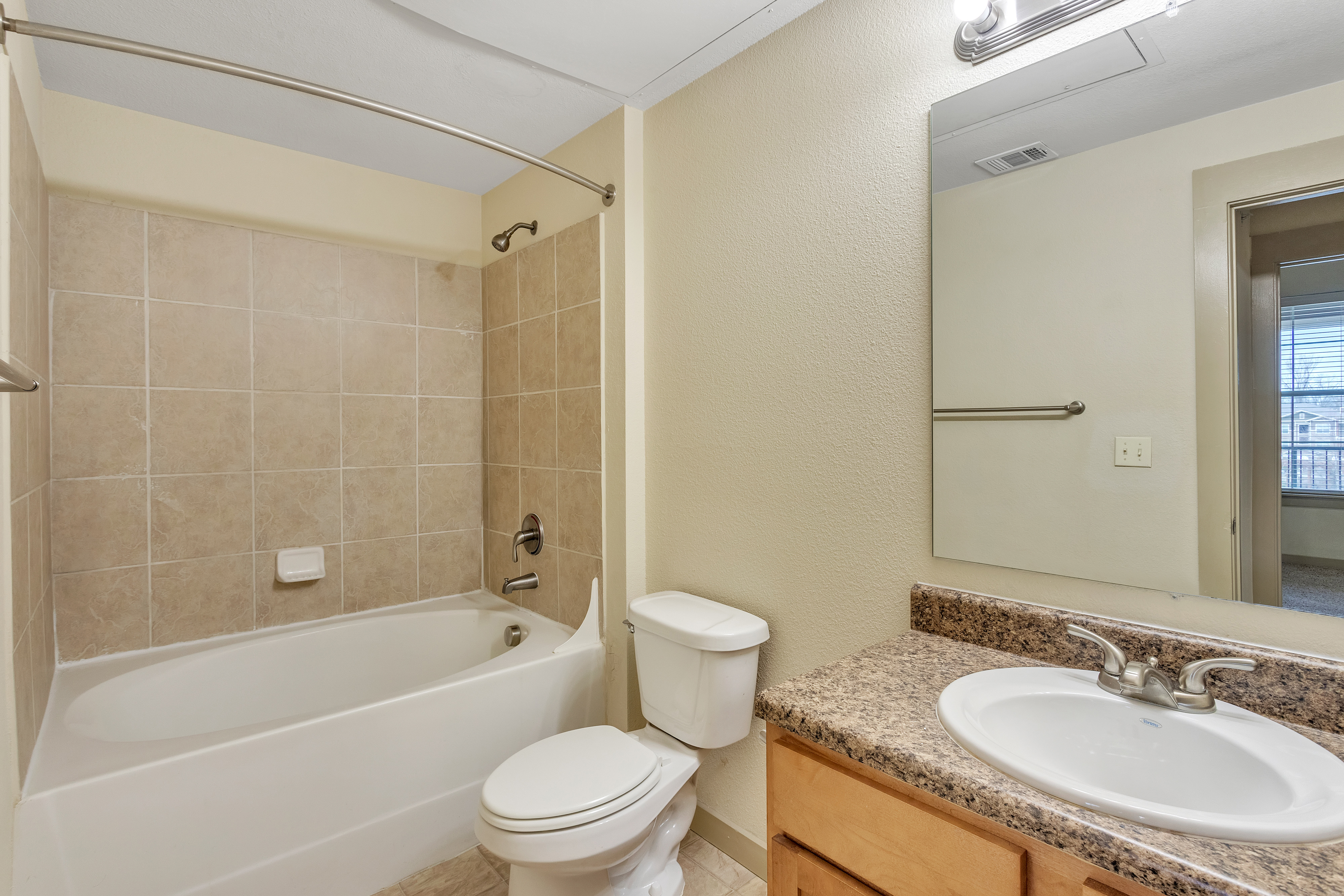 Bathroom with counter, mirror and curved shower rod Riverside at Rockwater Luxury Apartments North L