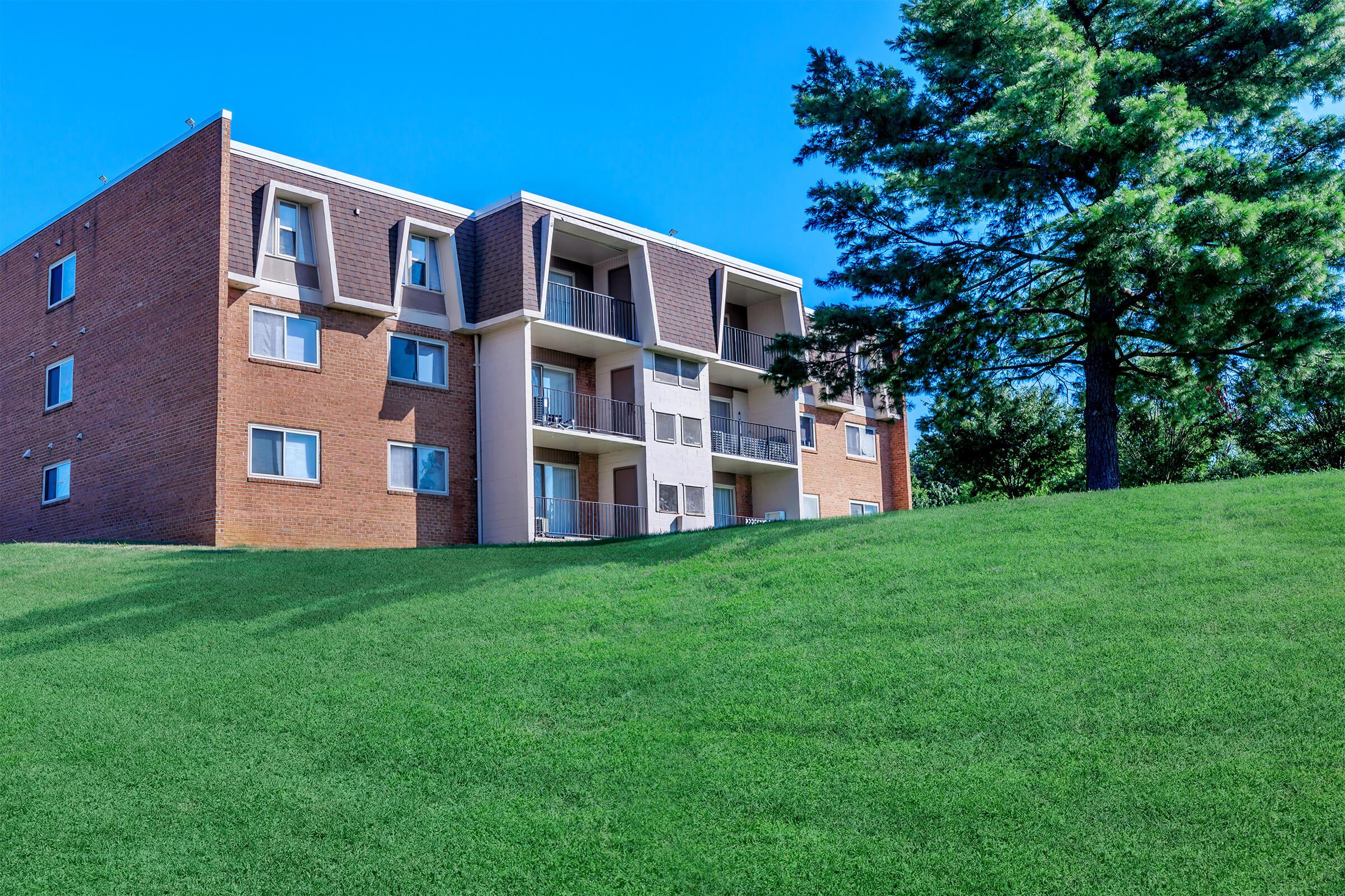 a large brick building with green grass