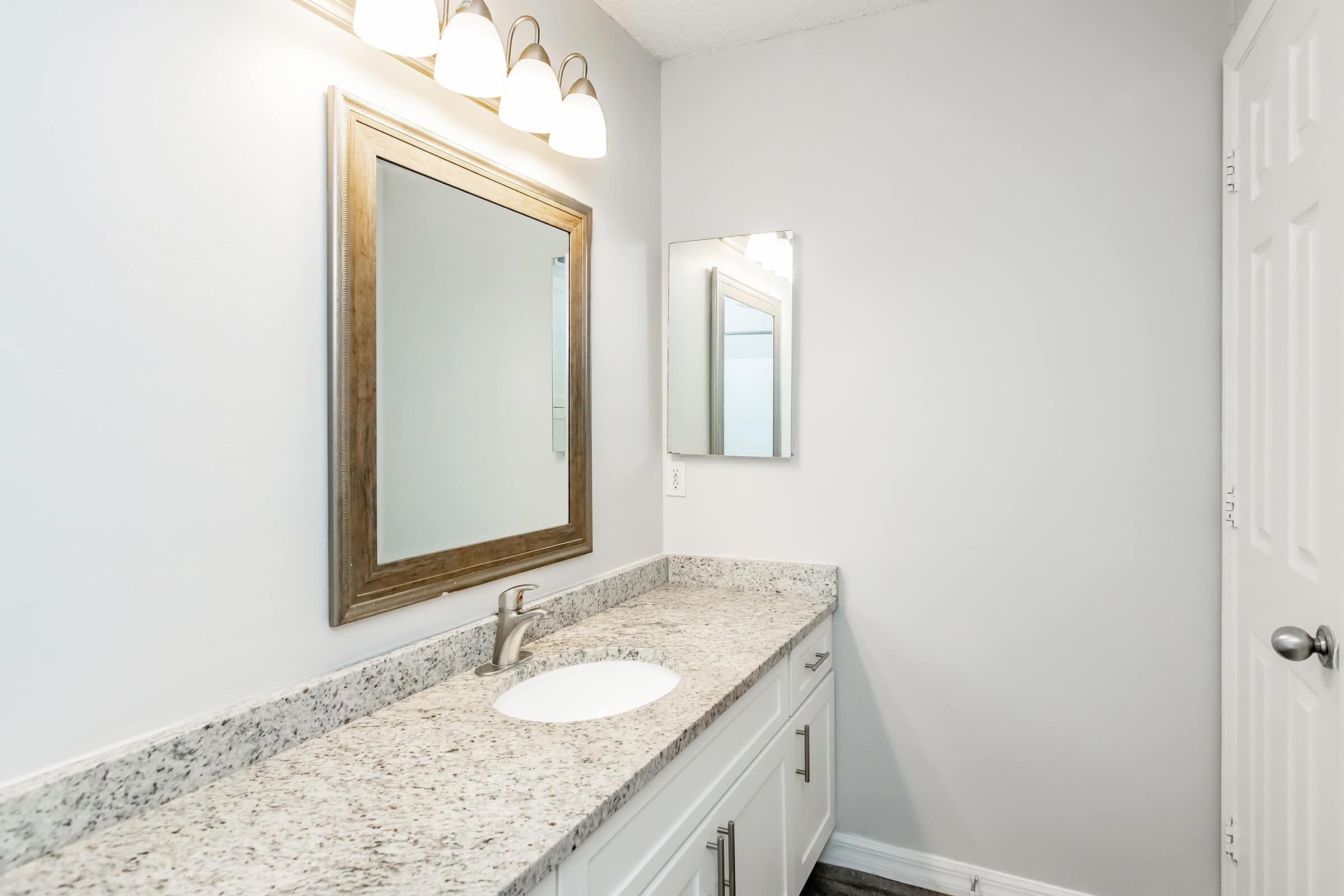 a bedroom area with a sink and a mirror