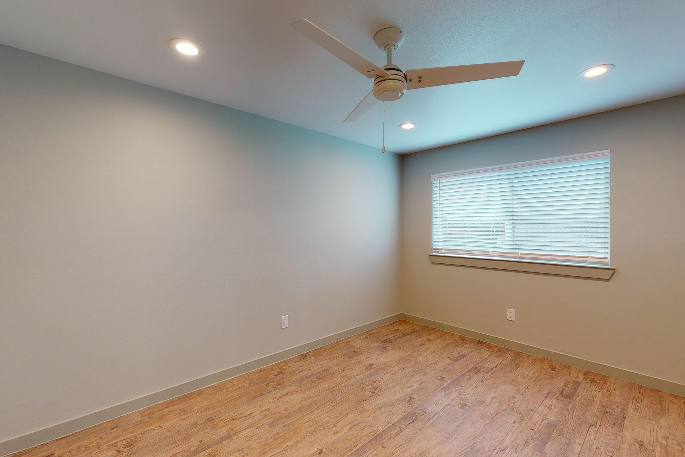 a vacant bedroom with a ceiling fan