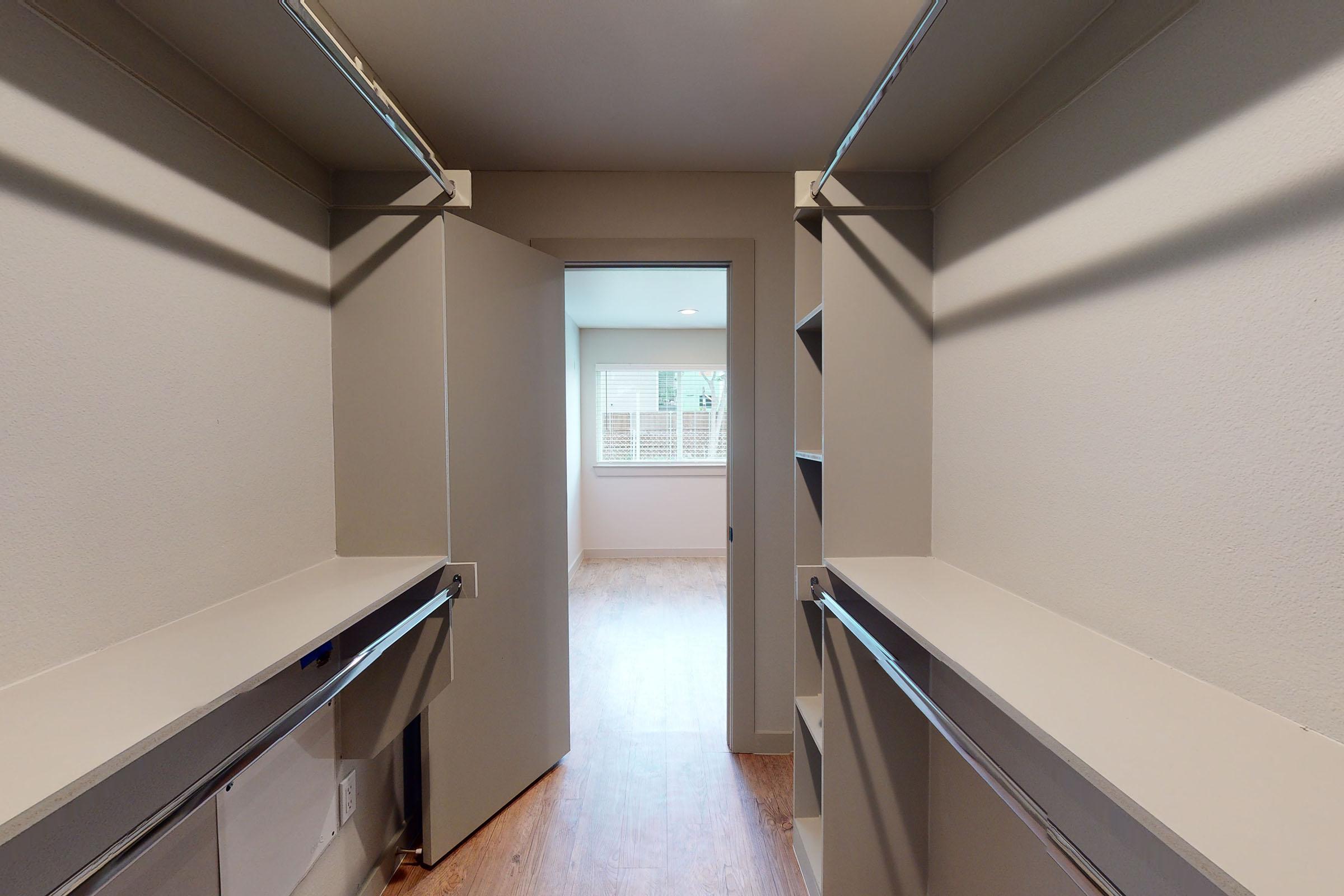 an unfurnished walk-in closet with wooden floors