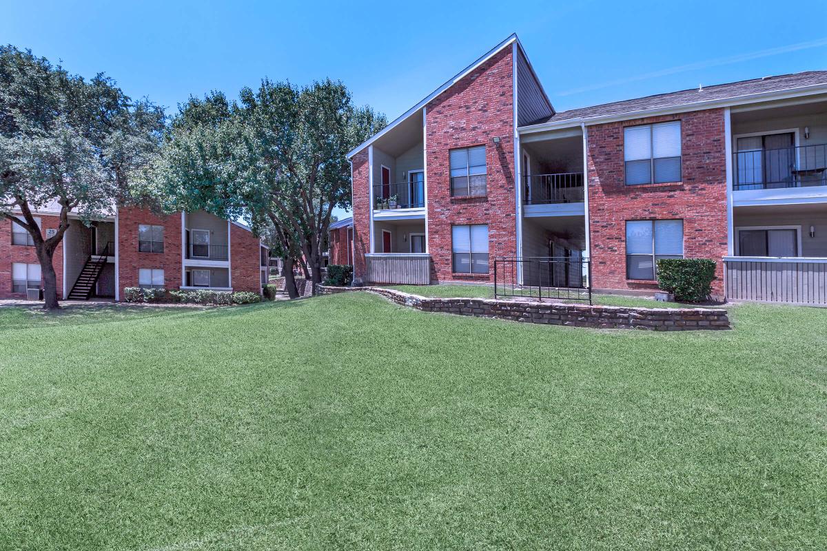 a house with a lawn in front of a brick building