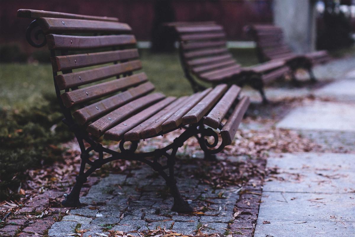 an empty park bench sitting on top of a wooden fence