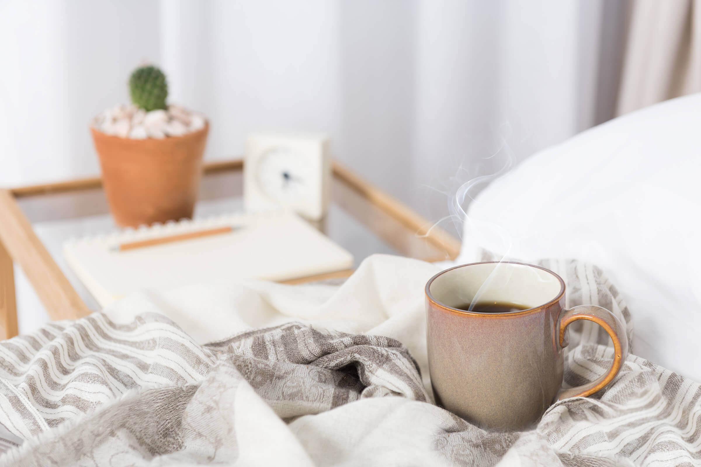 a cup of coffee sitting on top of a bed